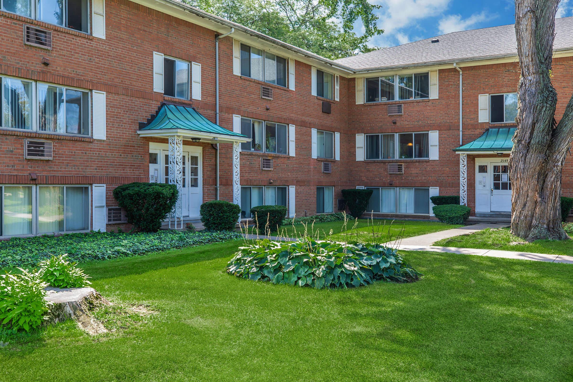 a house with a lawn in front of a brick building