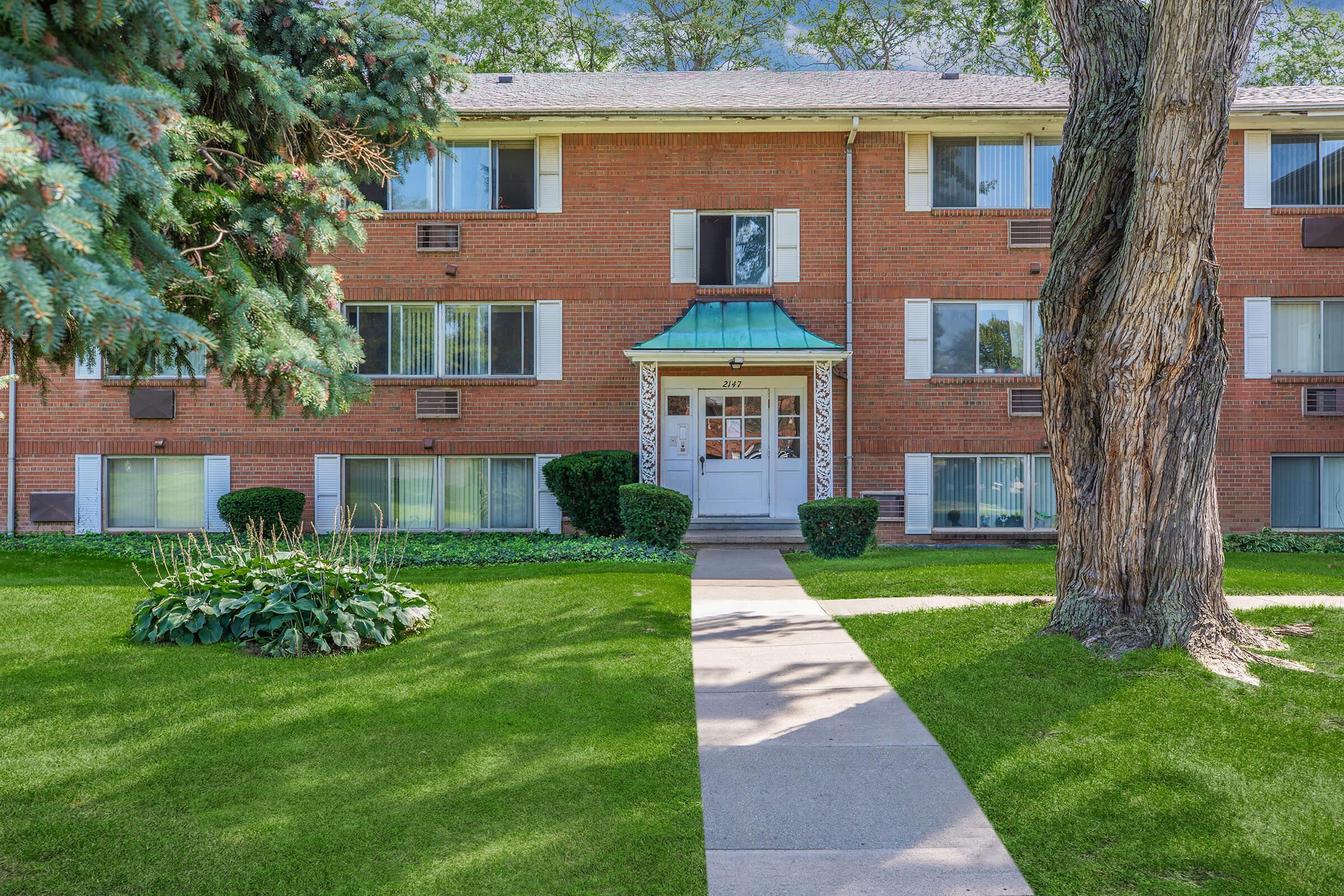 a house with a lawn in front of a brick building