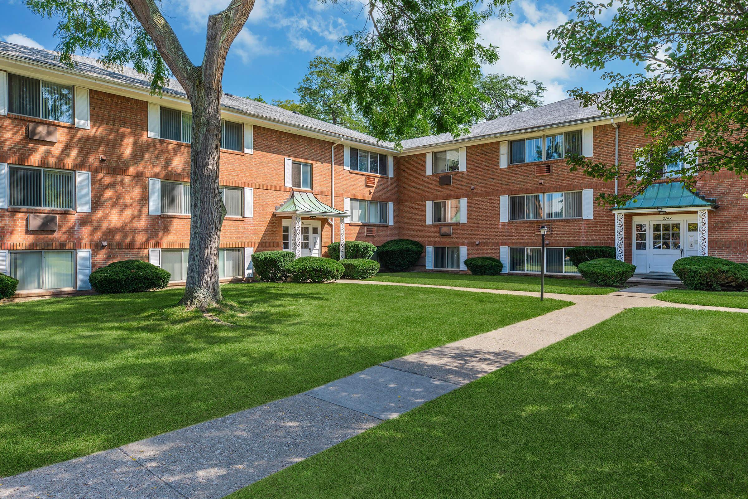 a large brick building with grass in front of a house