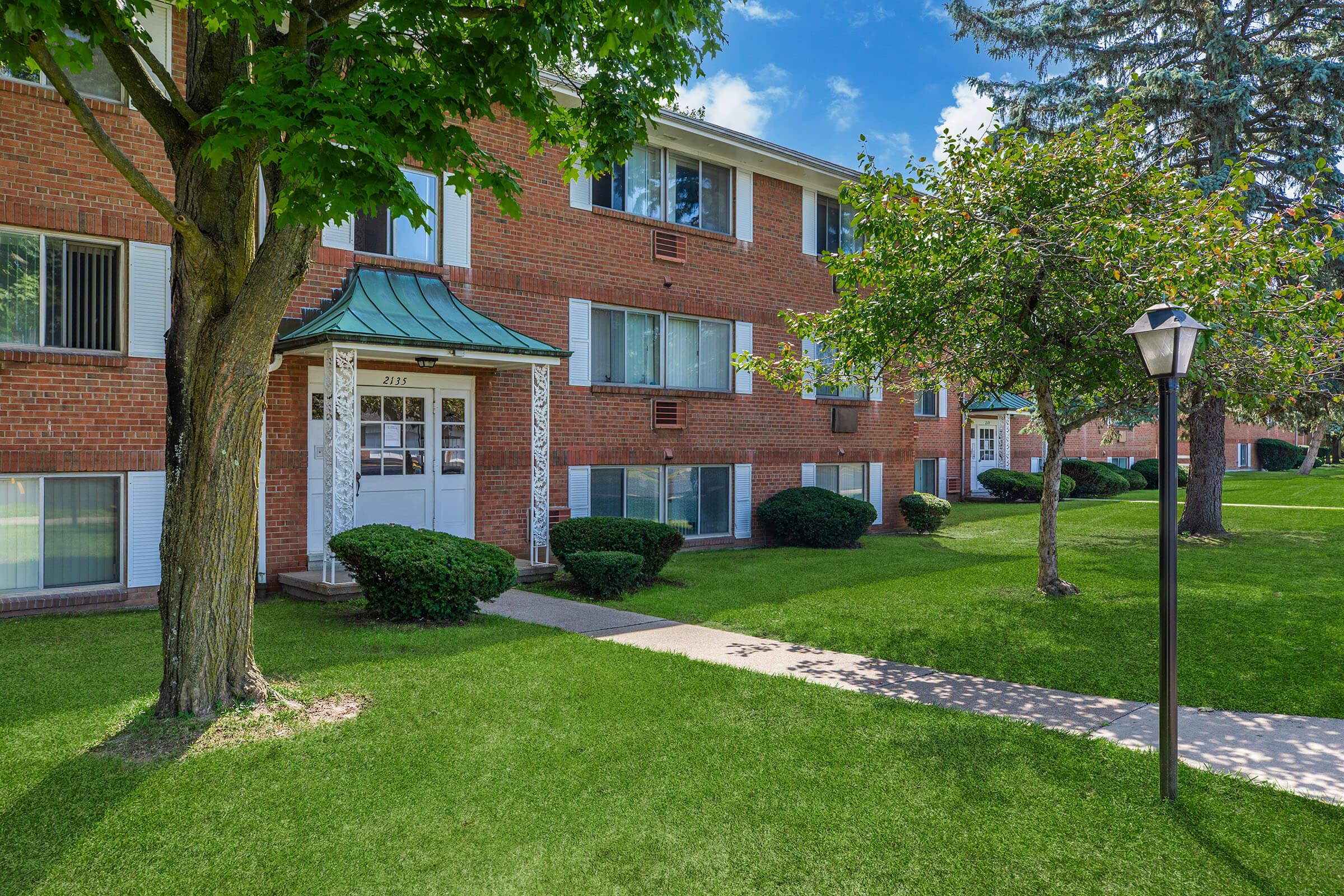 a house with a lawn in front of a brick building