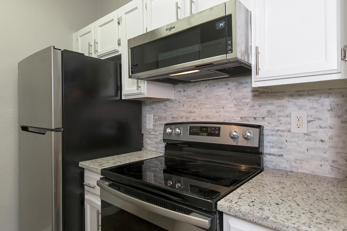 a stove top oven sitting inside of a kitchen with stainless steel appliances