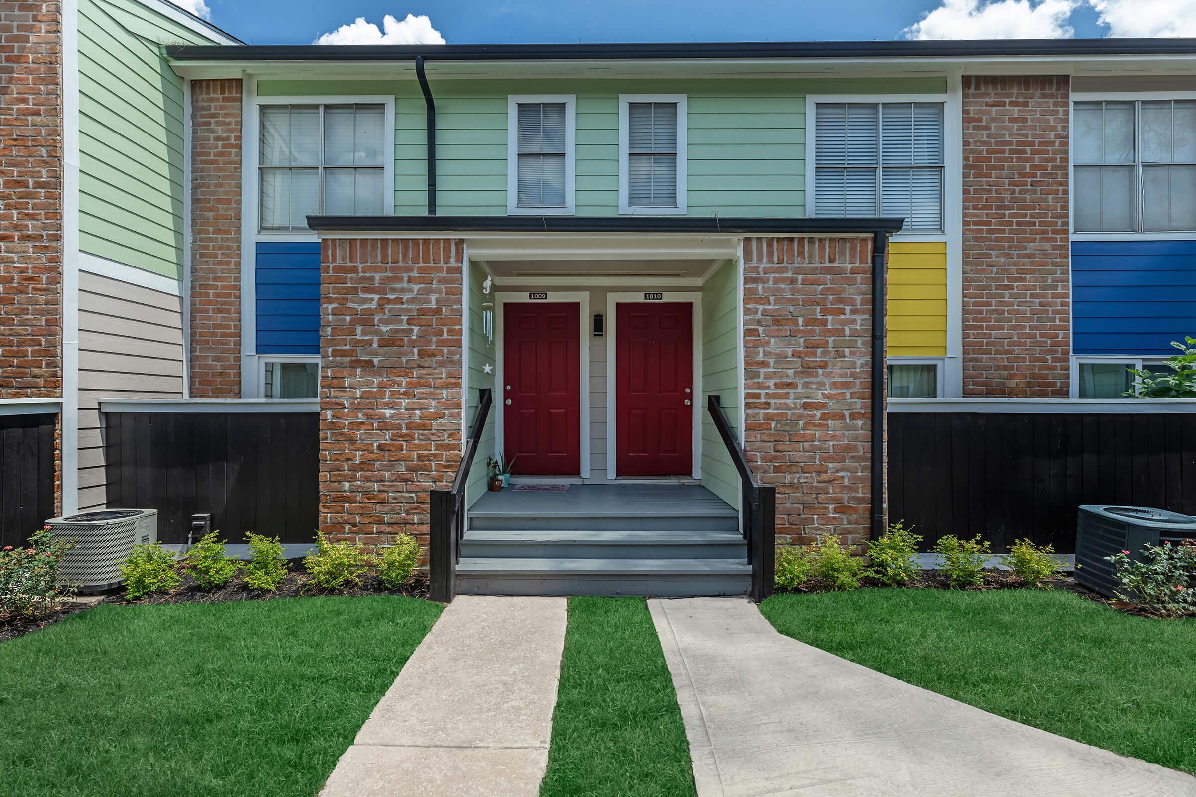 a house with a lawn in front of a brick building