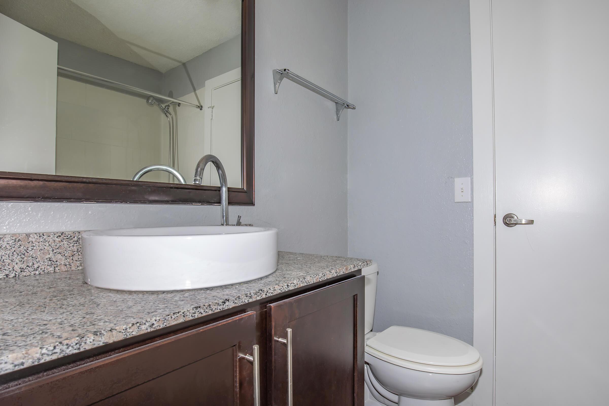 a white sink sitting under a mirror