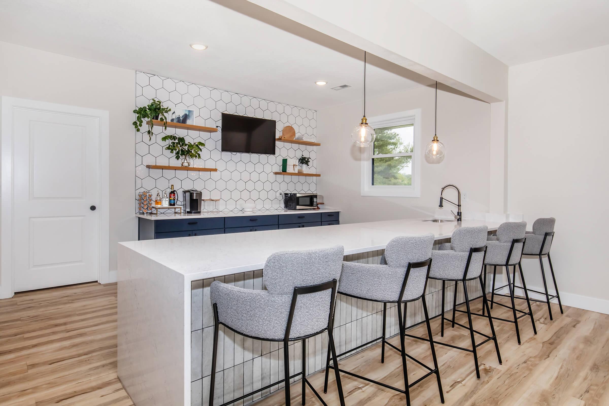 Resident kitchen and social lounge with island seating and decorative shelving at Bexley Urbandale.