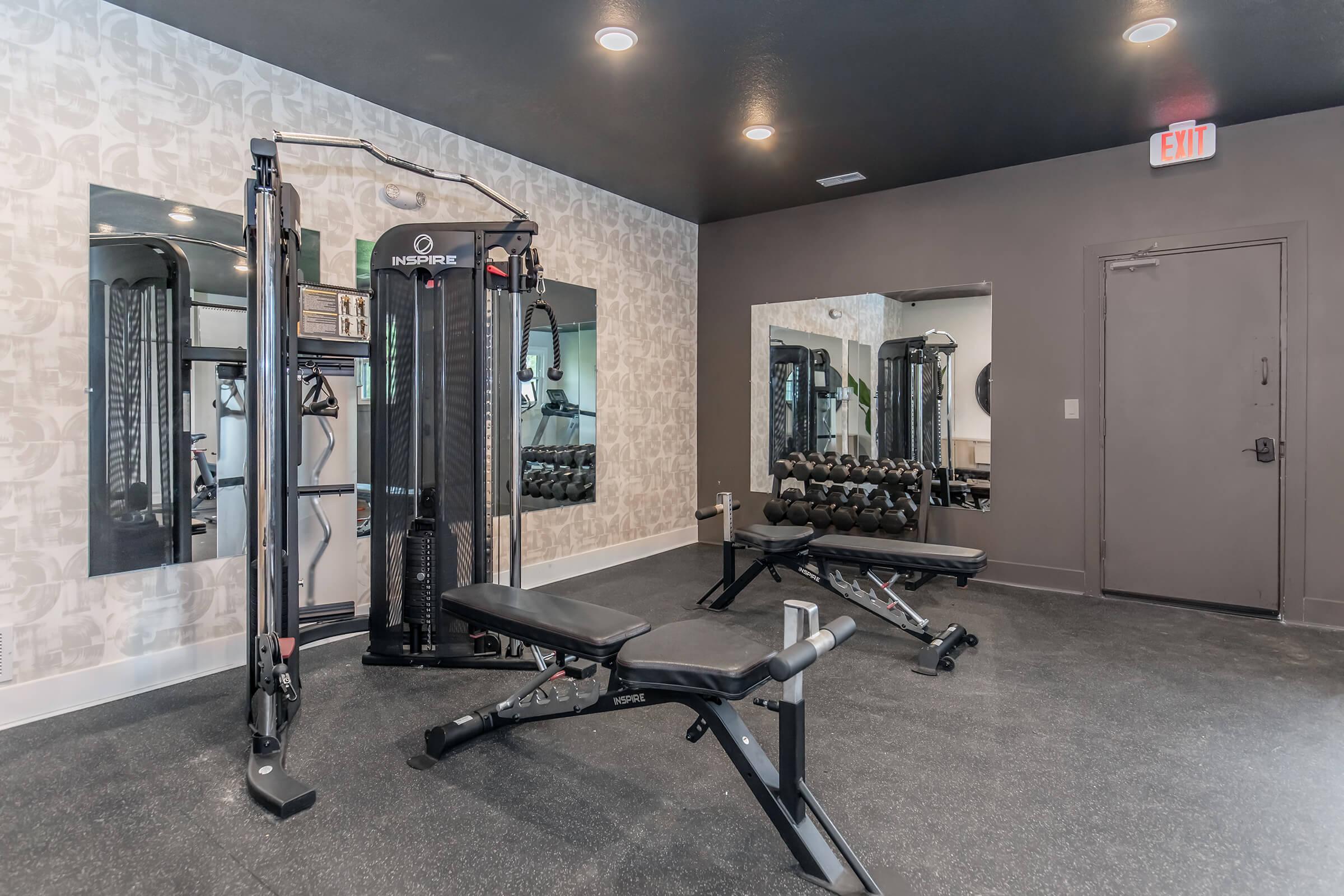 Fitness center with weight machines and mirrors in renovated Bexley apartment community.