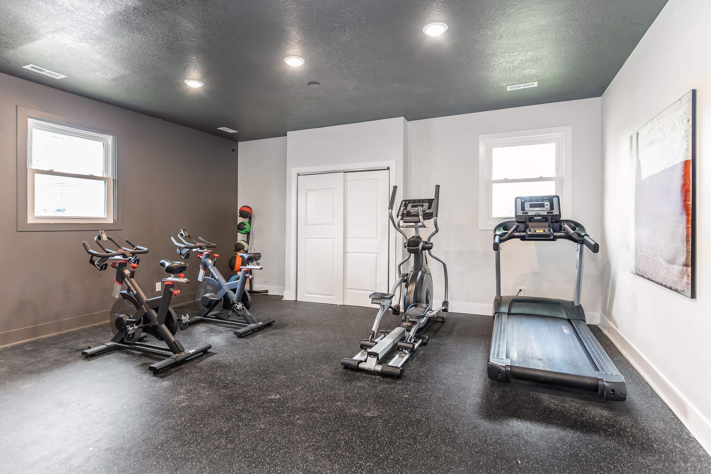 Cardio room with treadmill, exercise bike, and natural light at Bexley’s fully equipped fitness facility.