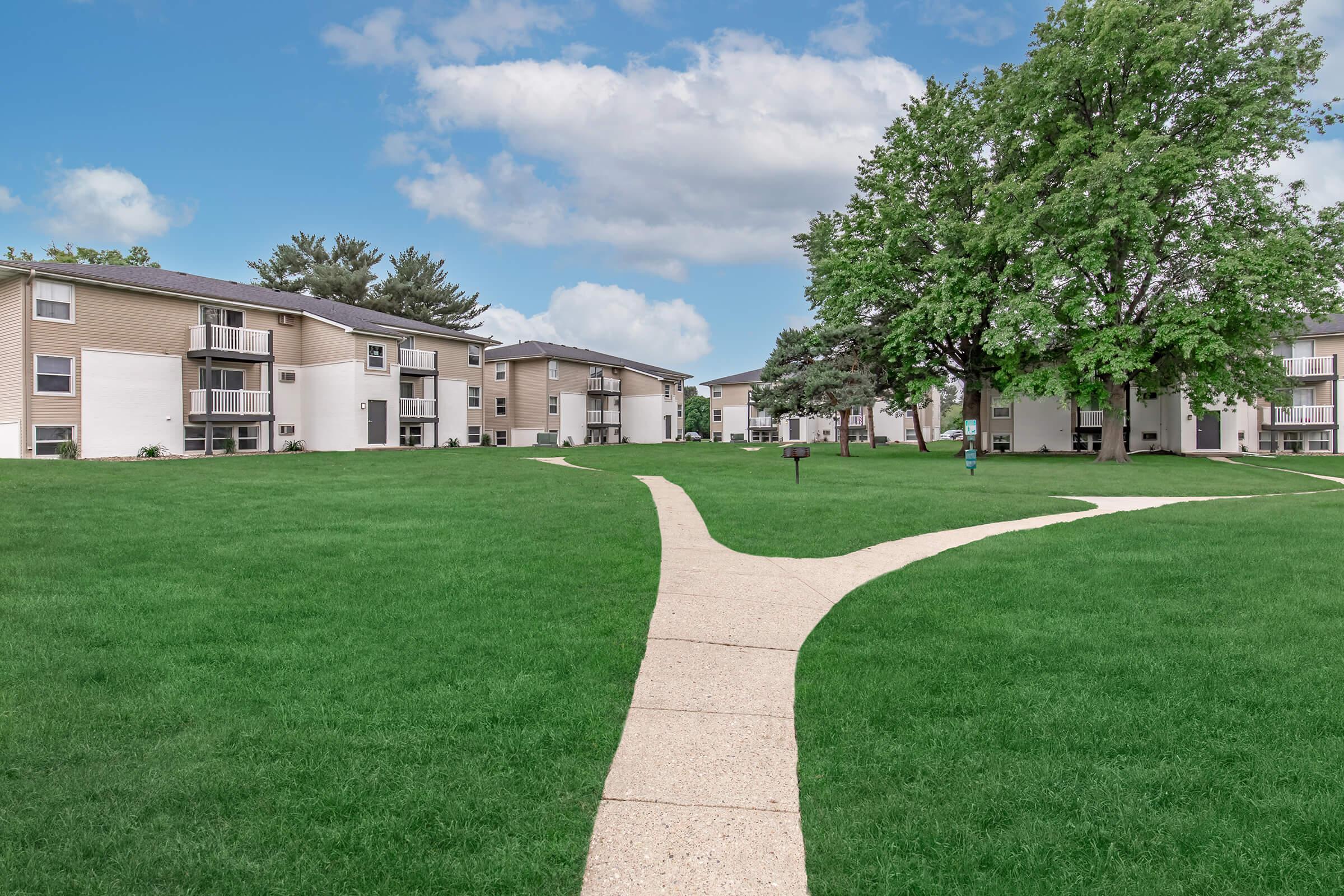 Walking path through green courtyard in front of Bexley’s modern apartment buildings.