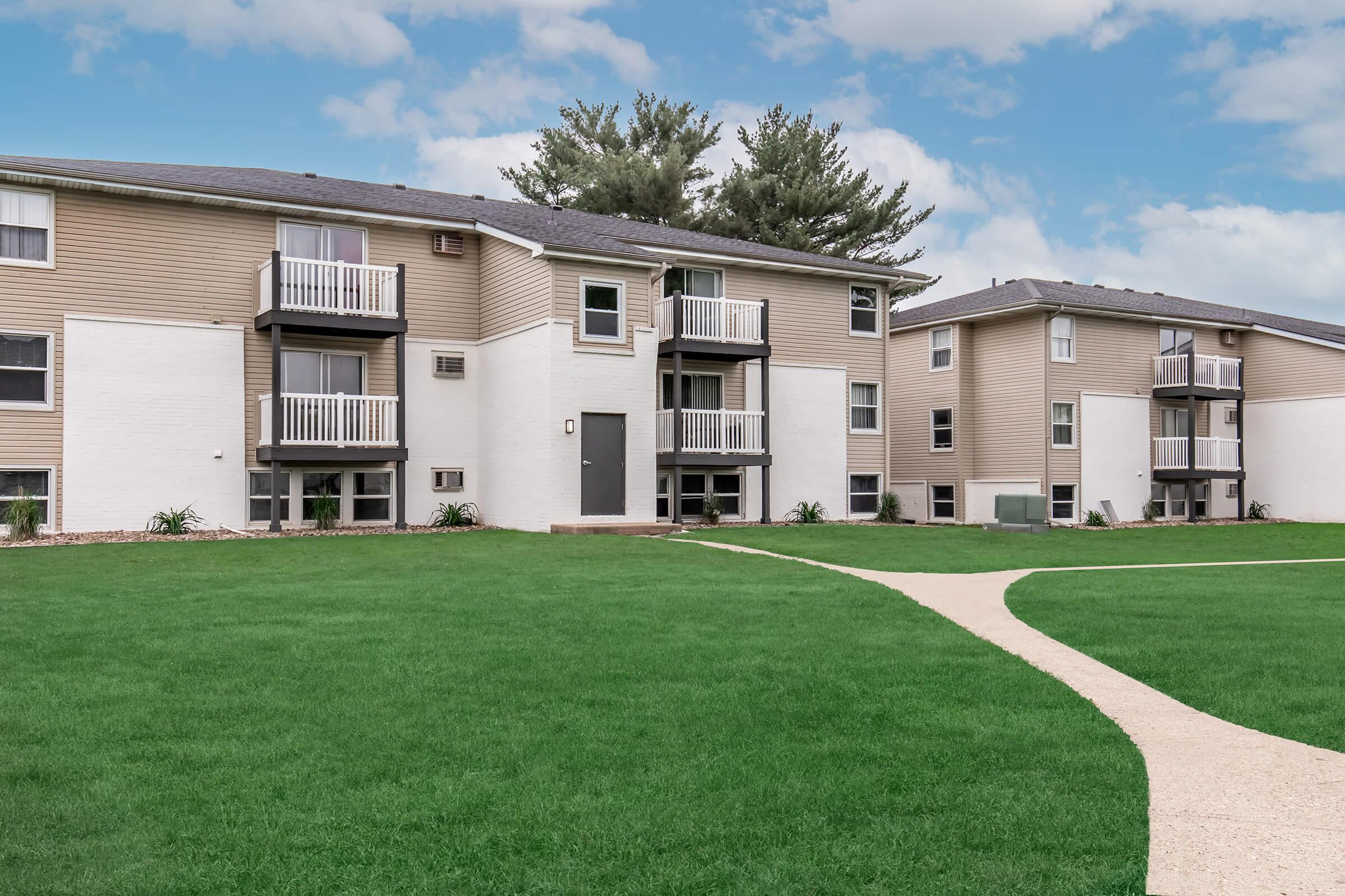 Side view of white exterior buildings and green lawn at Bexley Apartments in Urbandale, IA.