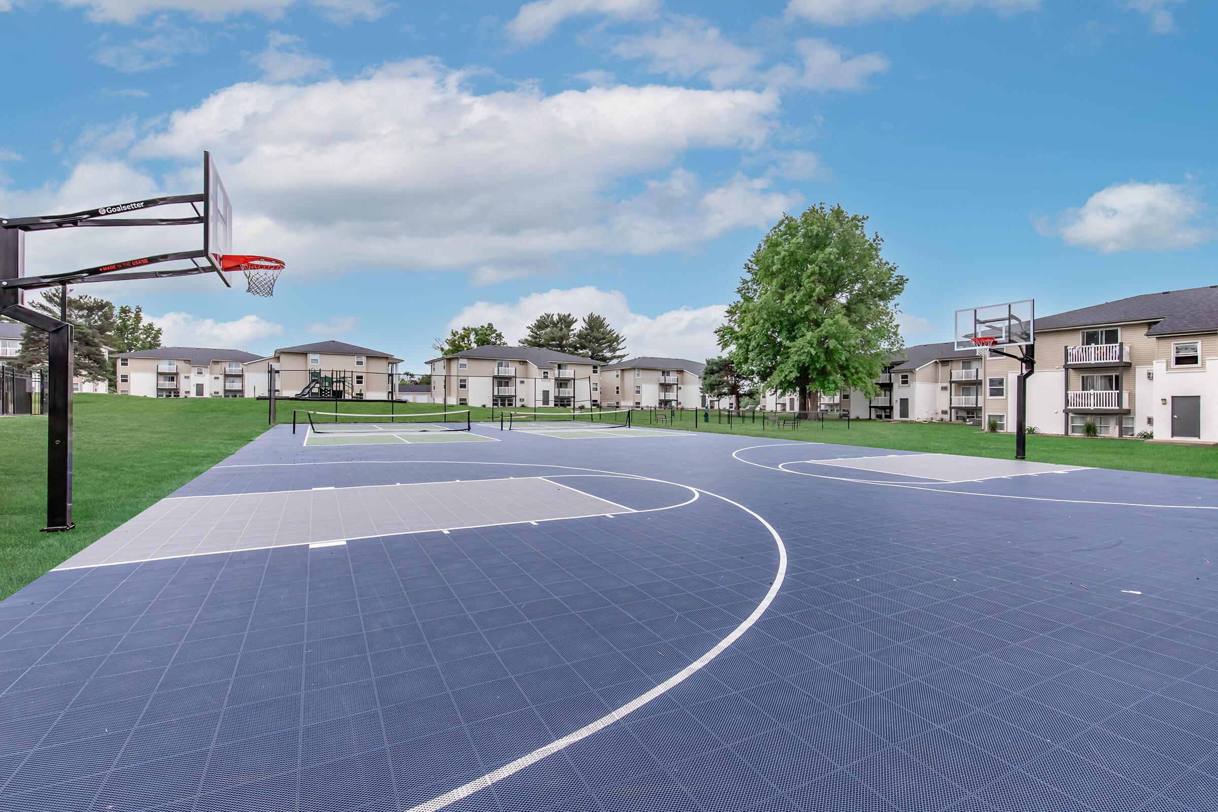 Basketball court with curved design and tree-lined backdrop at Bexley Apartments in Urbandale, IA.
