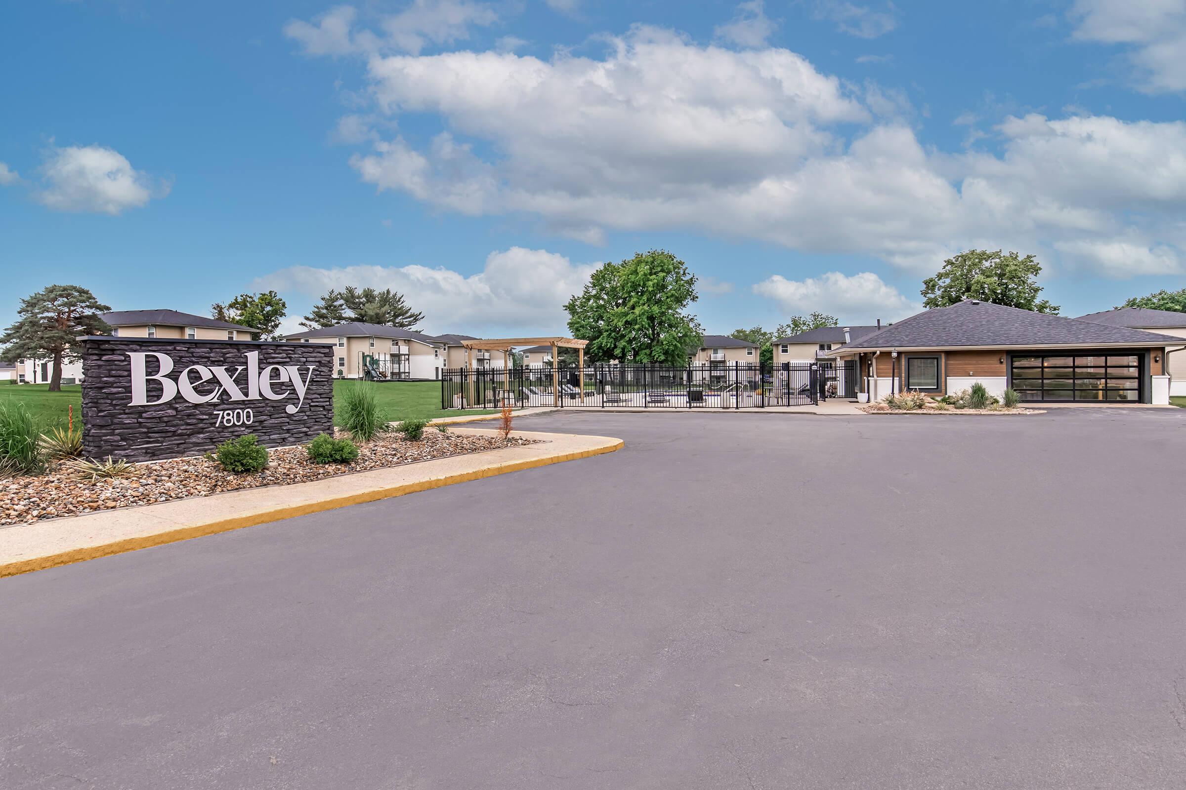Wide asphalt driveway leading to Bexley entrance sign and leasing office in Urbandale, Iowa.