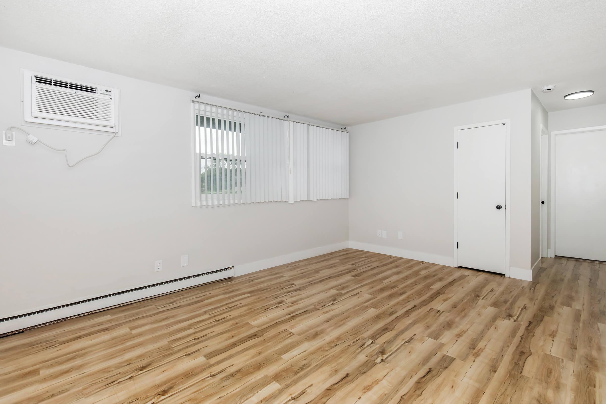 Renovated living room with wood-style flooring, neutral walls, and large windows in Bexley Urbandale apartment.