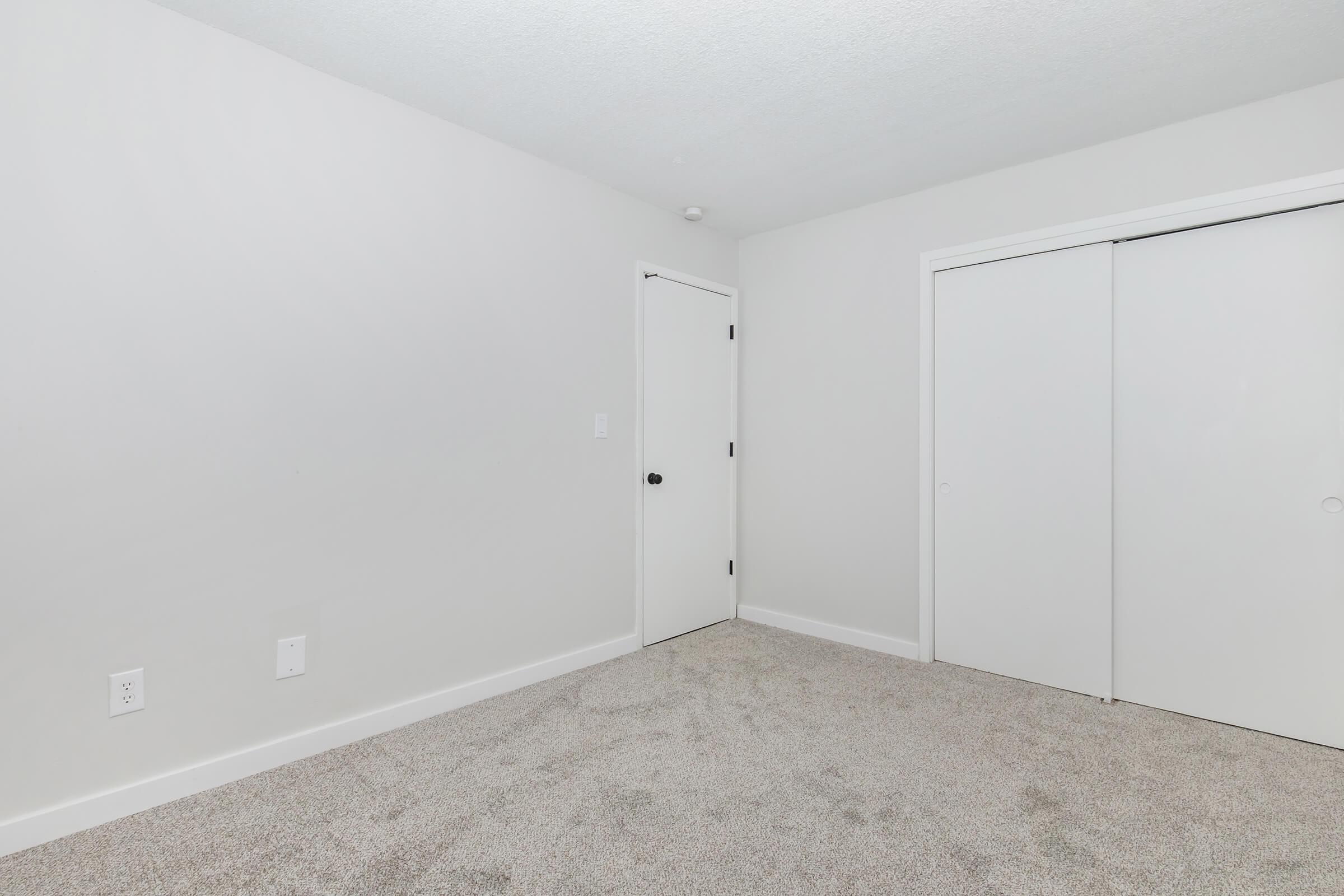Spacious bedroom with plush carpet and sliding closet doors in a renovated Bexley apartment.