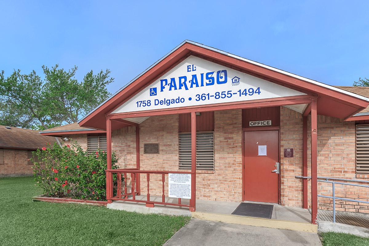 a red brick building with grass in front of a house