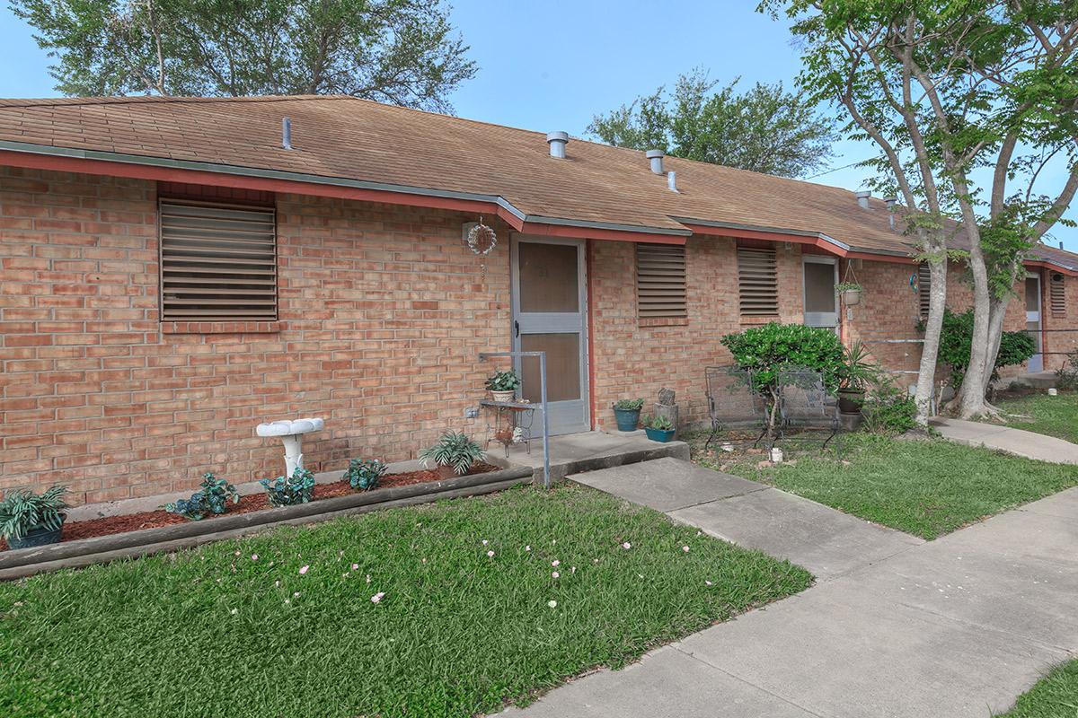 a large brick building with grass in front of a house