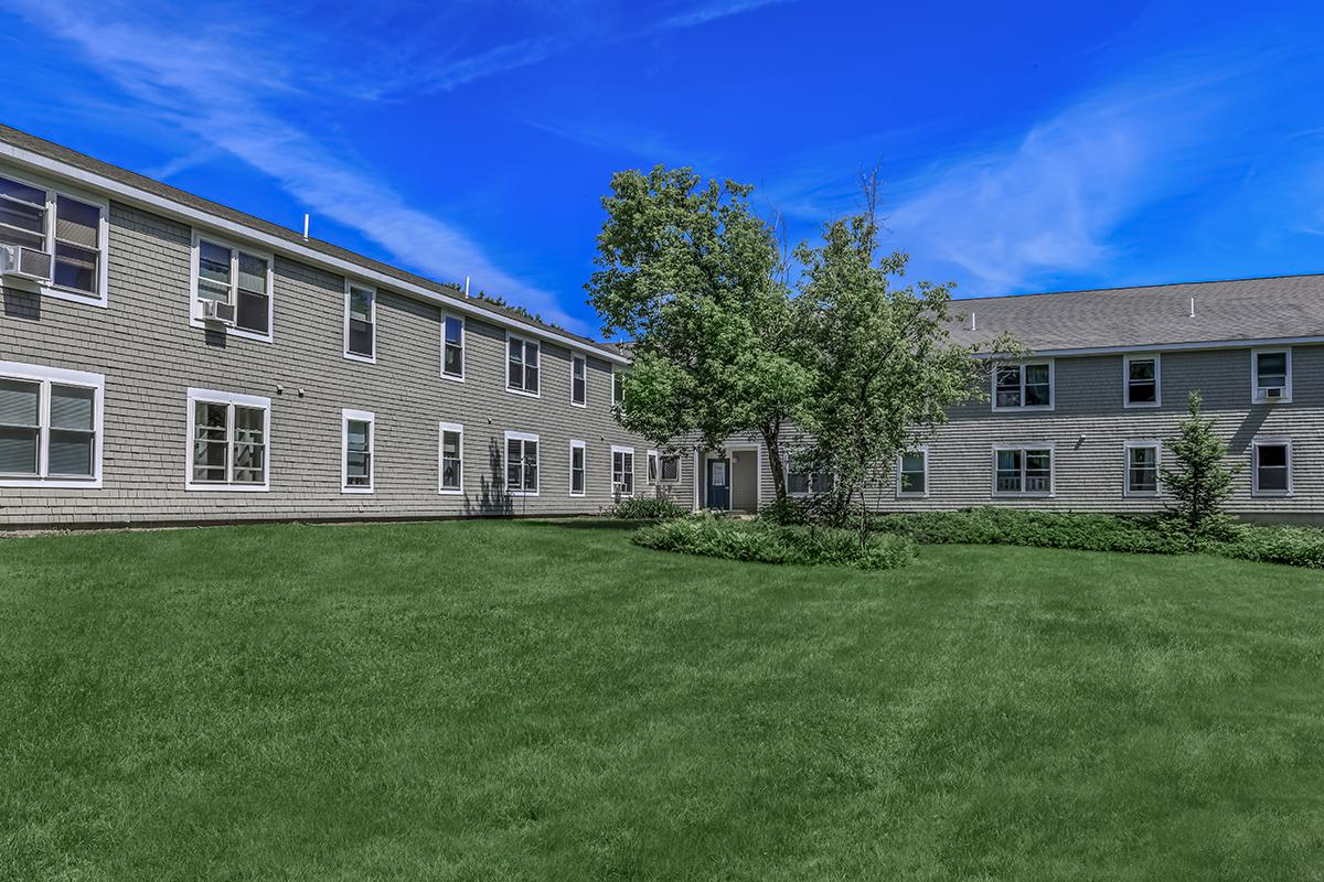 a large brick building with grass in front of a house