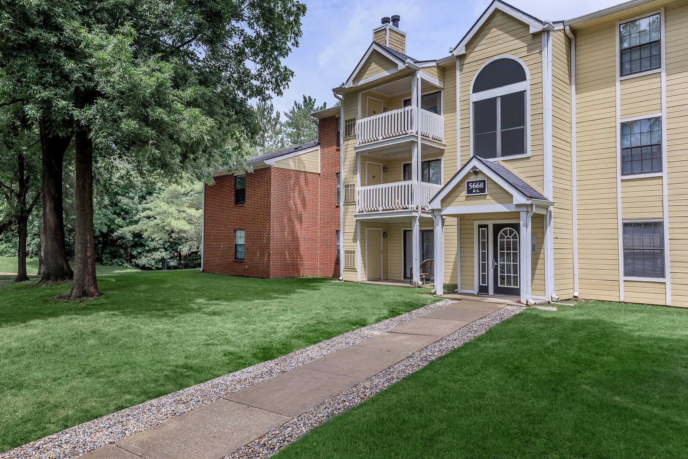 a large brick building with grass in front of a house