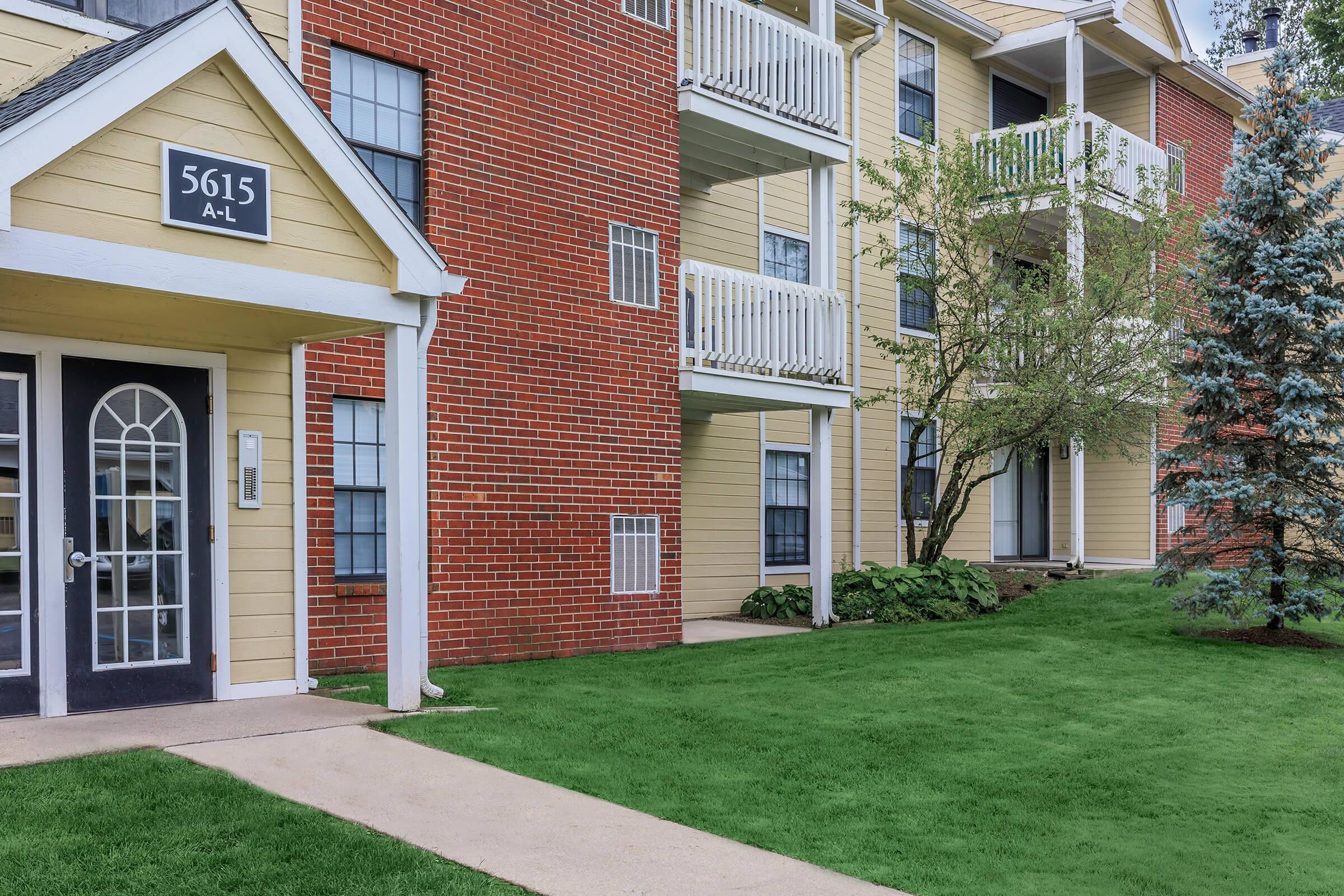 a large brick building with grass in front of a house