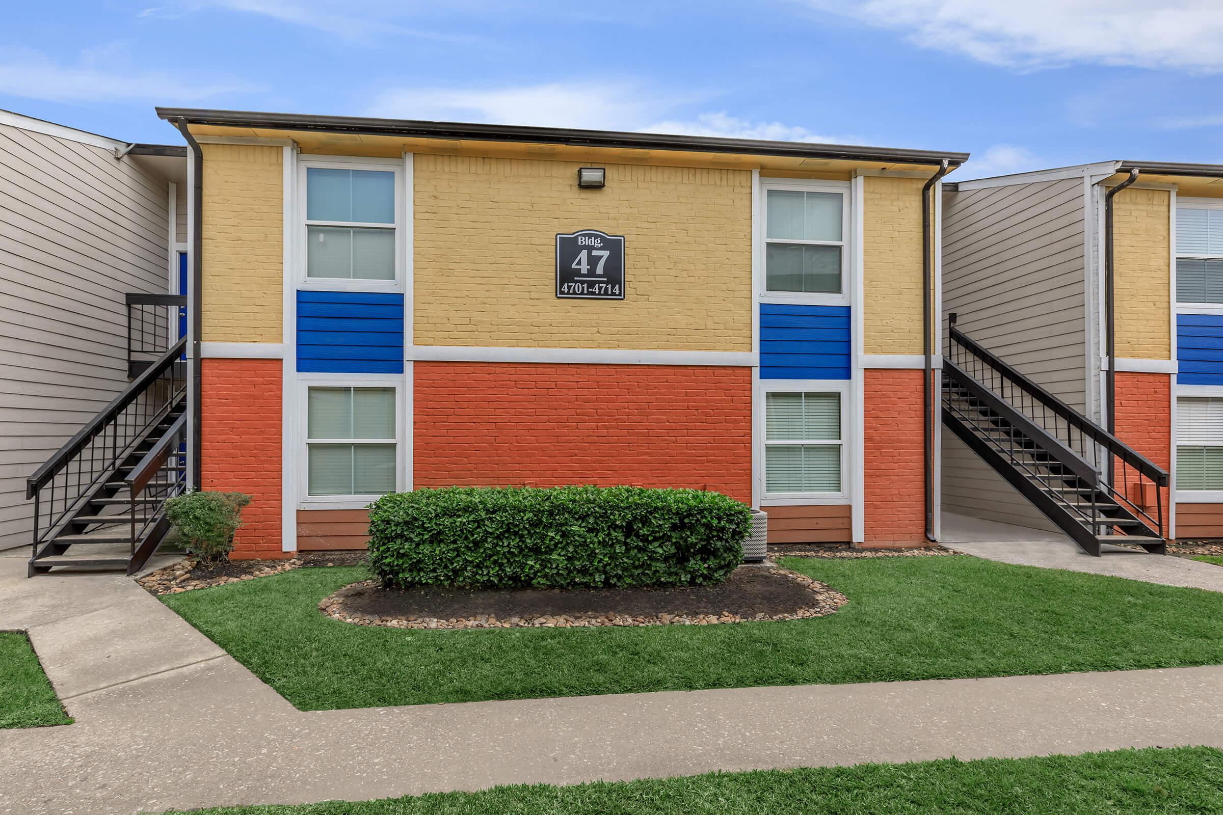 a house with a lawn in front of a brick building