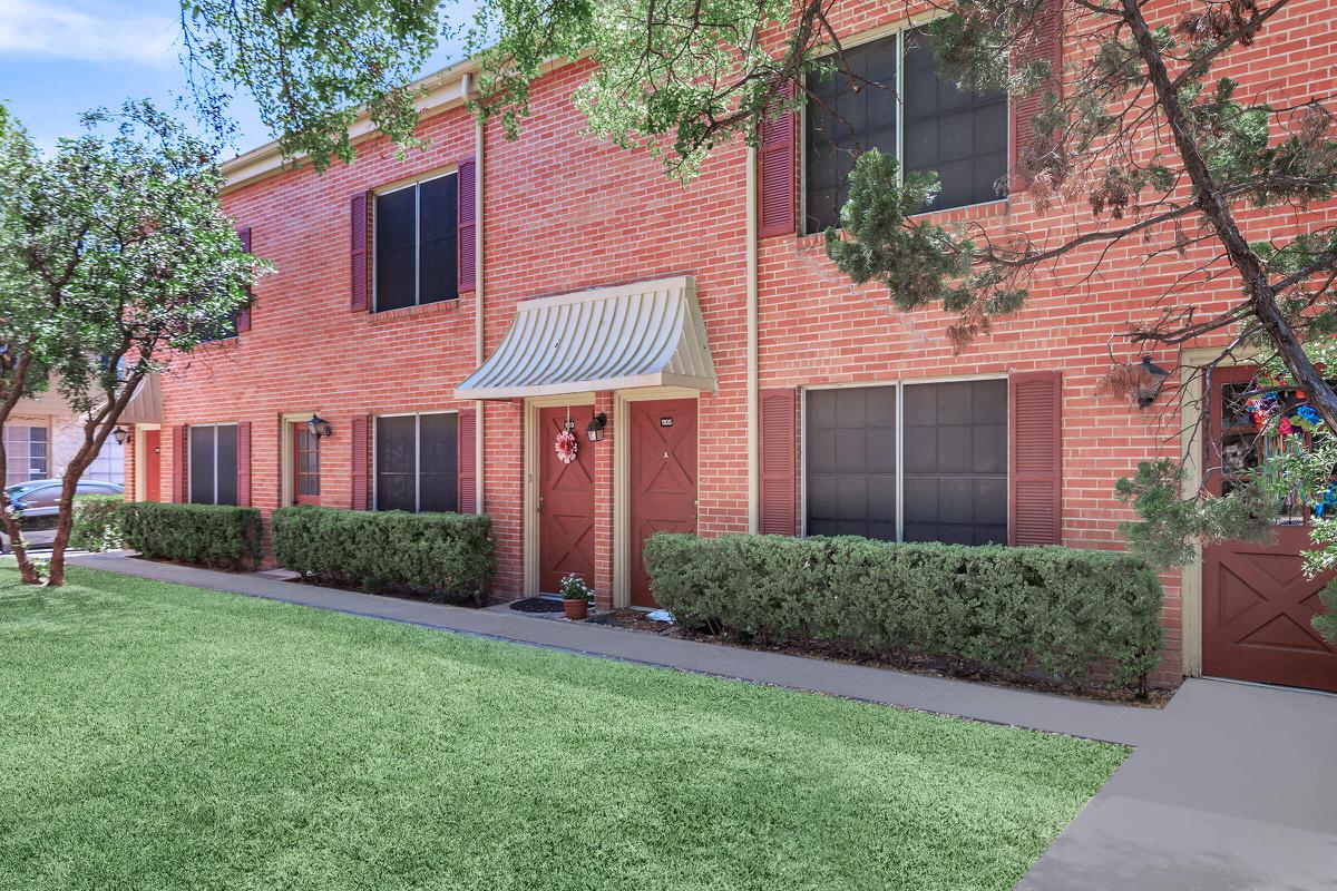 a large brick building with grass in front of a house