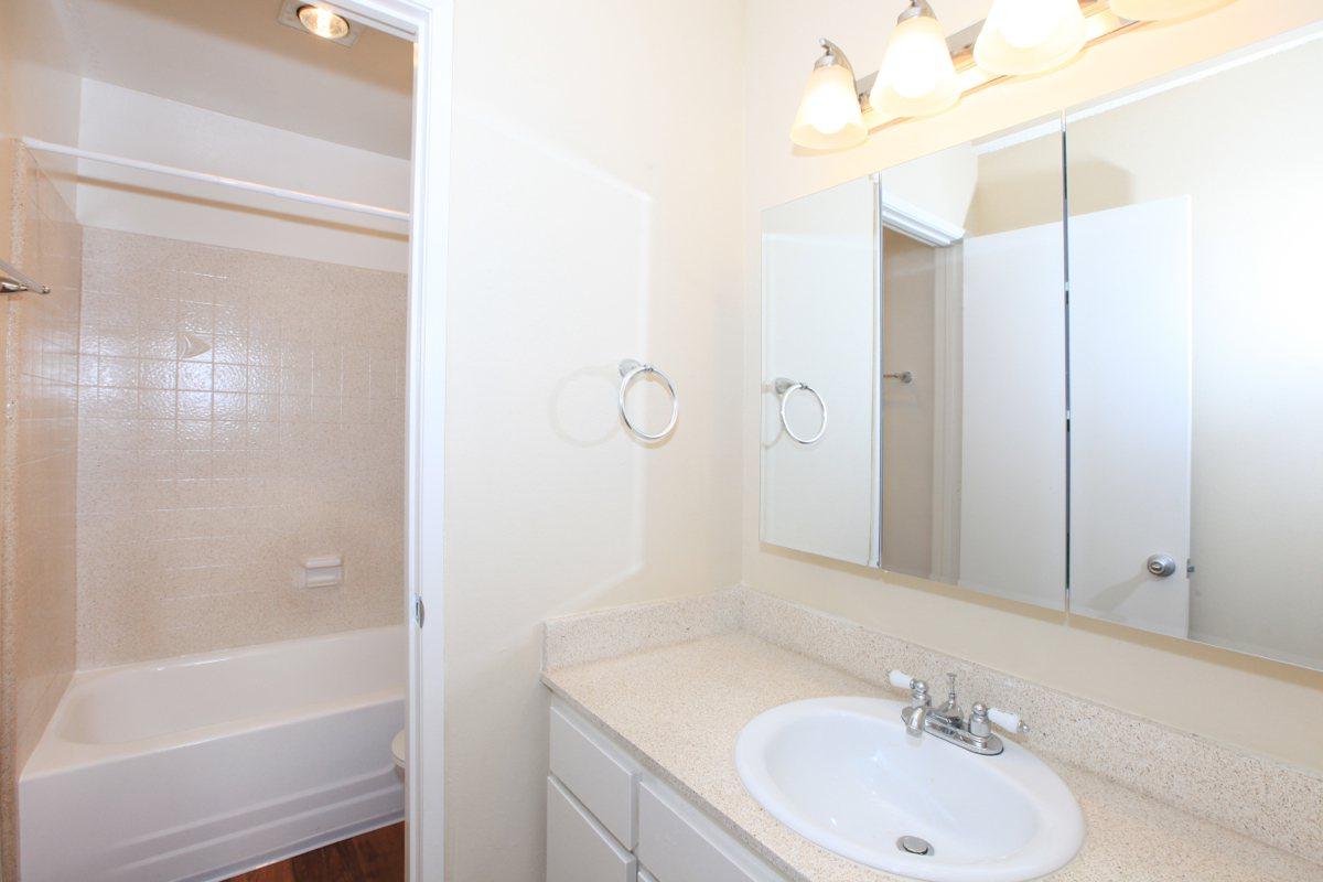 a white sink sitting under a mirror