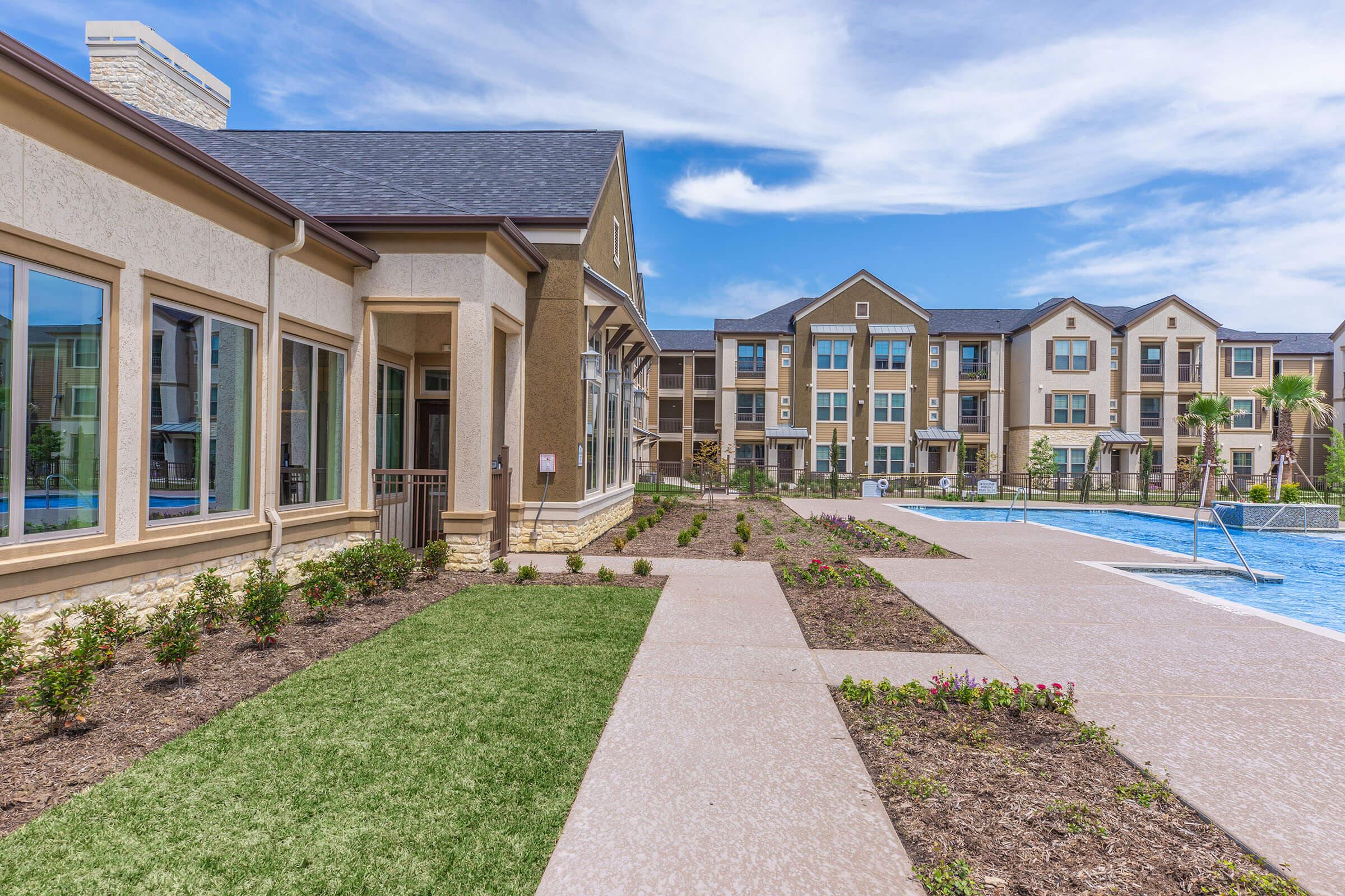 a path with grass in front of a building