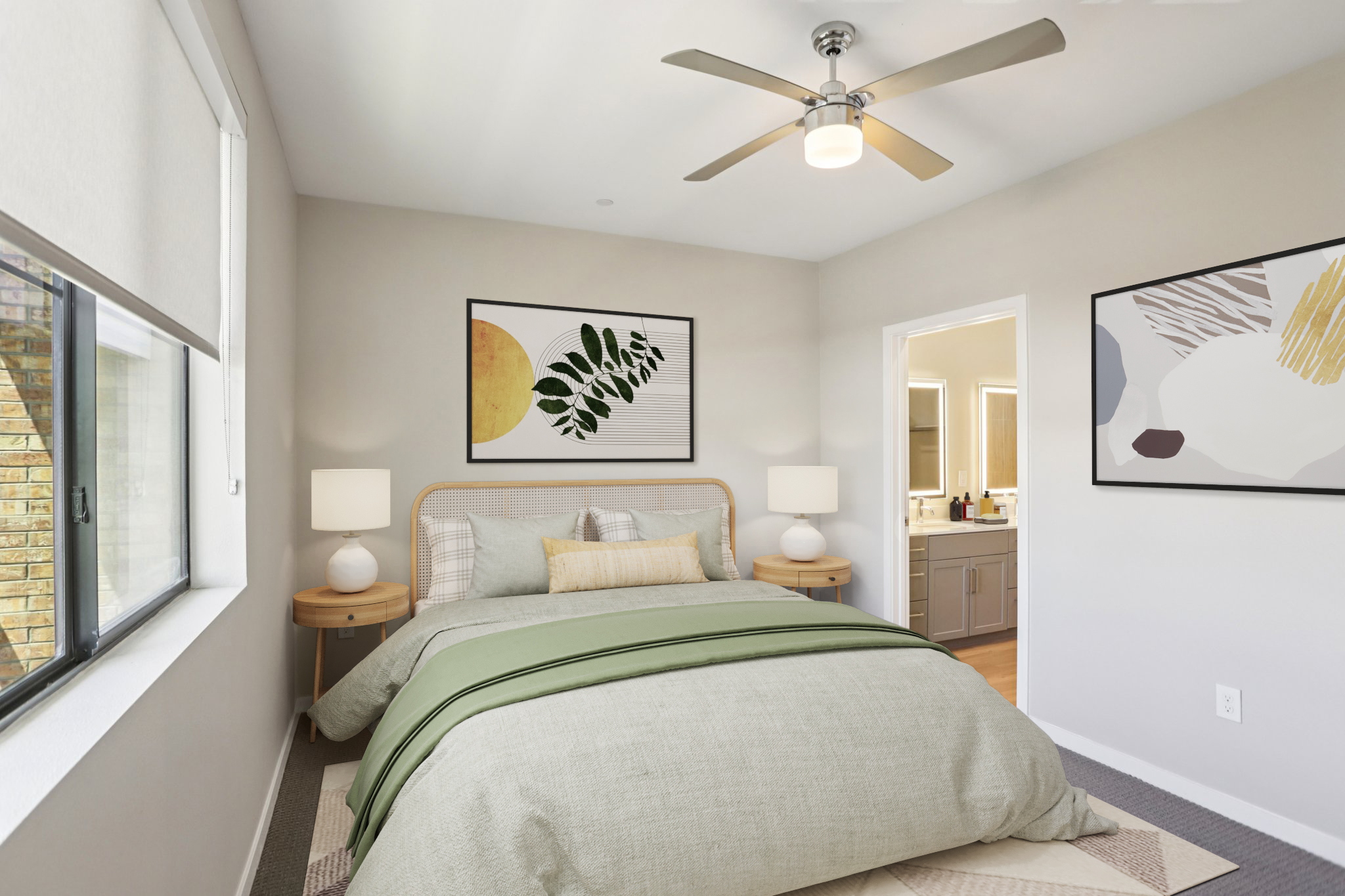 A well-decorated bedroom featuring a queen-sized bed with a light green blanket, two bedside tables with lamps, and modern art on the walls. The room has ample natural light from a large window, a ceiling fan, and an adjoining bathroom visible through an open door. The decor combines neutral tones with subtle green accents.