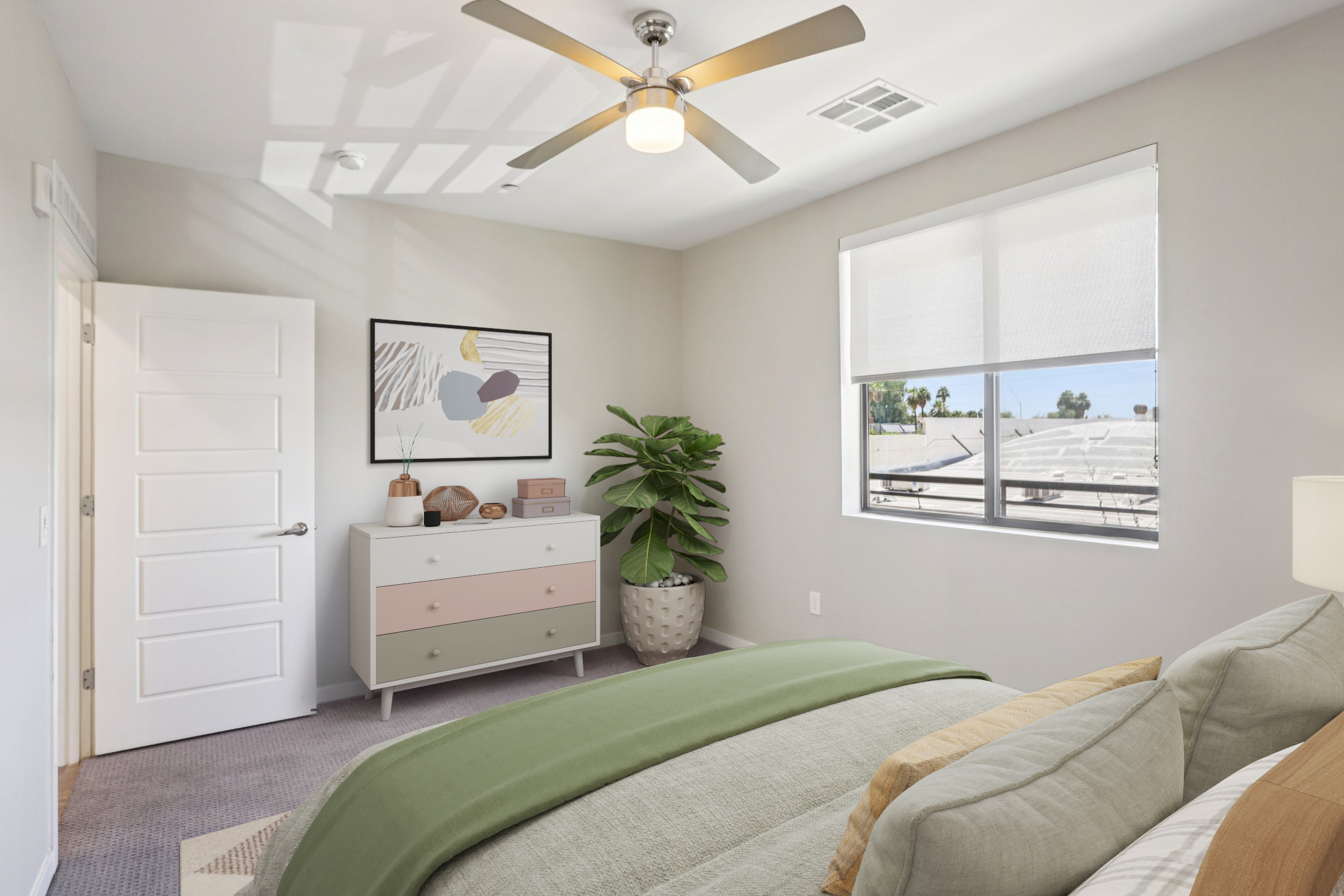 A modern bedroom featuring a bed with green bedding, a light fan on the ceiling, a dresser with pastel drawers, a potted plant, and a wall art piece. Large windows allow natural light to fill the room, creating a bright and inviting atmosphere.