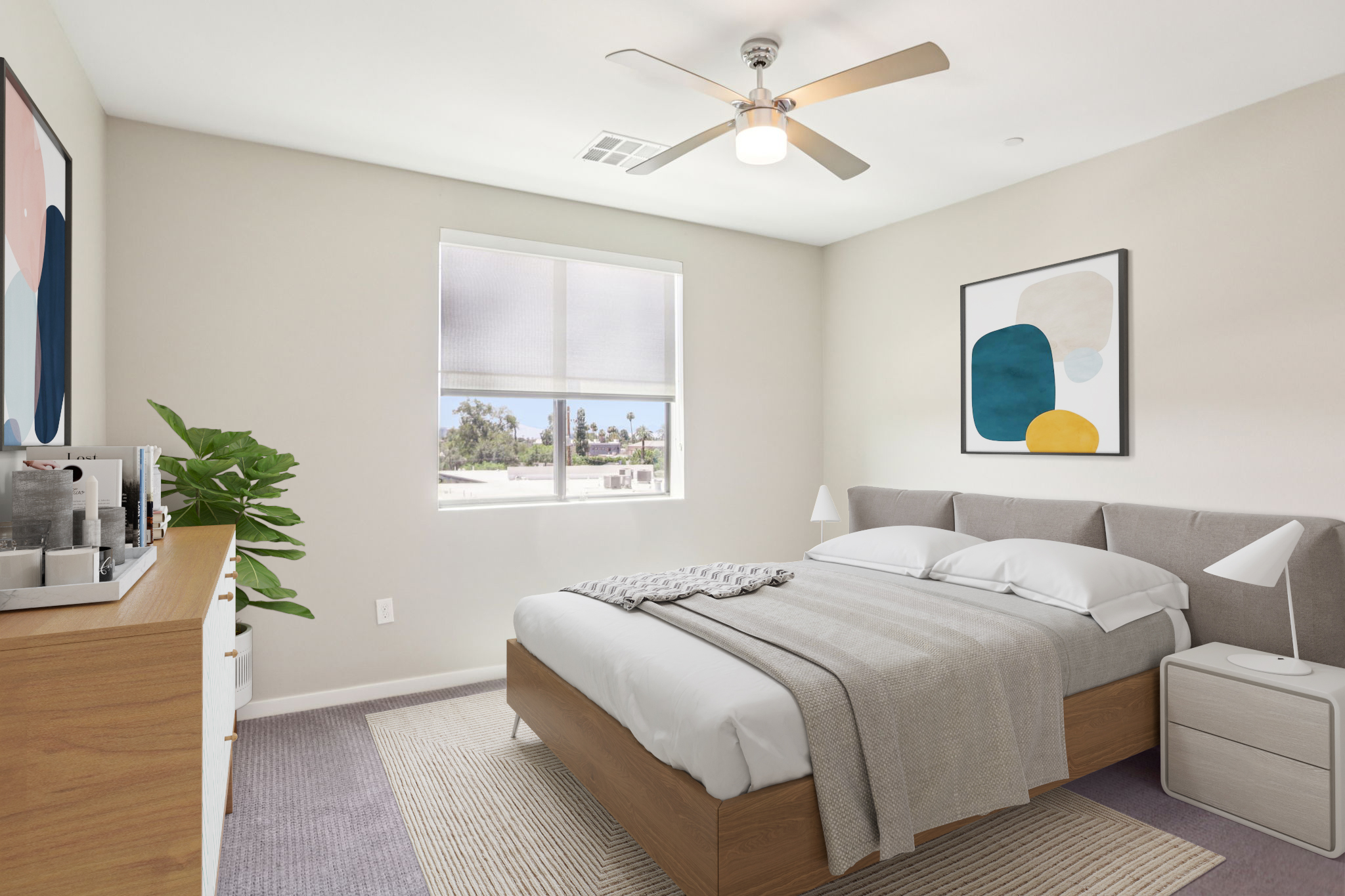 A cozy bedroom featuring a neatly made bed with white linens and a light gray throw. There’s a modern ceiling fan, a stylish wall art piece above the bed, a plant in the corner, and a dresser with decorative items. A window provides natural light and a view of palm trees outside.