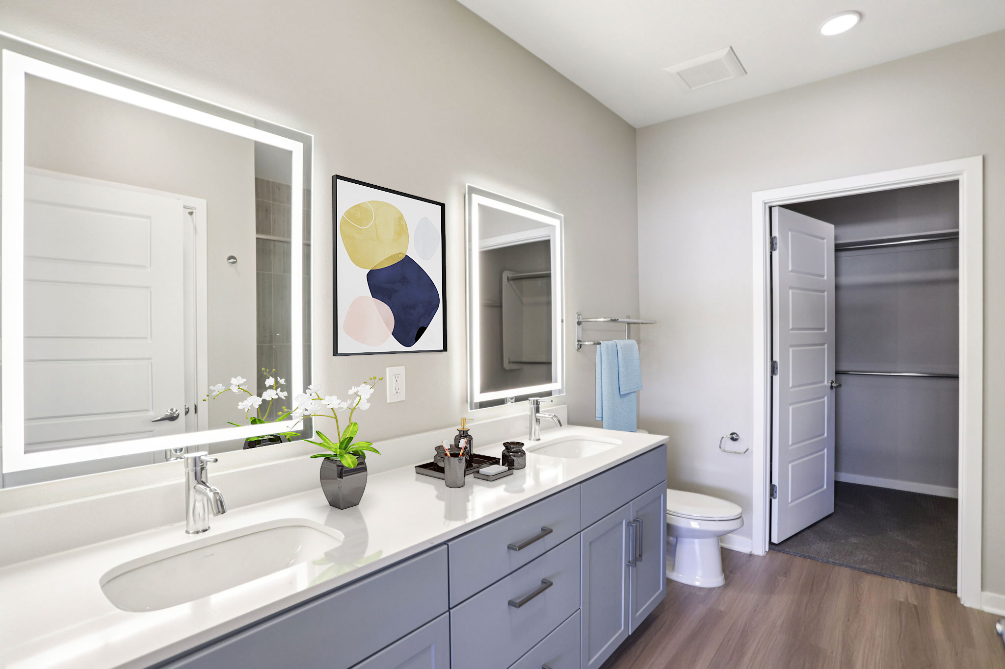 Modern bathroom featuring dual sinks with illuminated mirrors, a minimalist decor style, a towel rack, and a small plant. The walls are painted in a light color, and a closed closet door is visible in the background. The flooring is wooden.