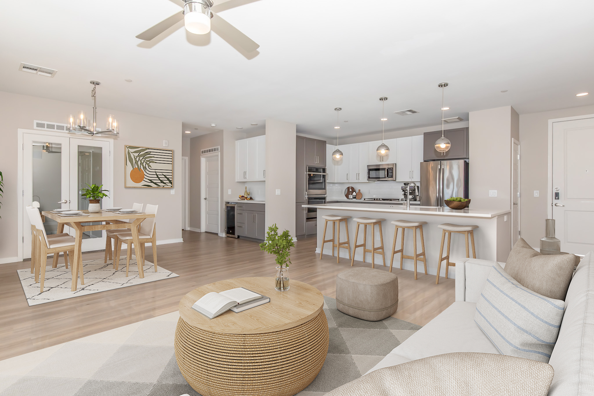 A modern open-concept living space featuring a cozy seating area with a light-colored sofa and round coffee table, an elegant dining area with a wooden table and chairs, and a sleek kitchen with stainless steel appliances. The decor is neutral and stylish, with a cozy rug and plant accents.