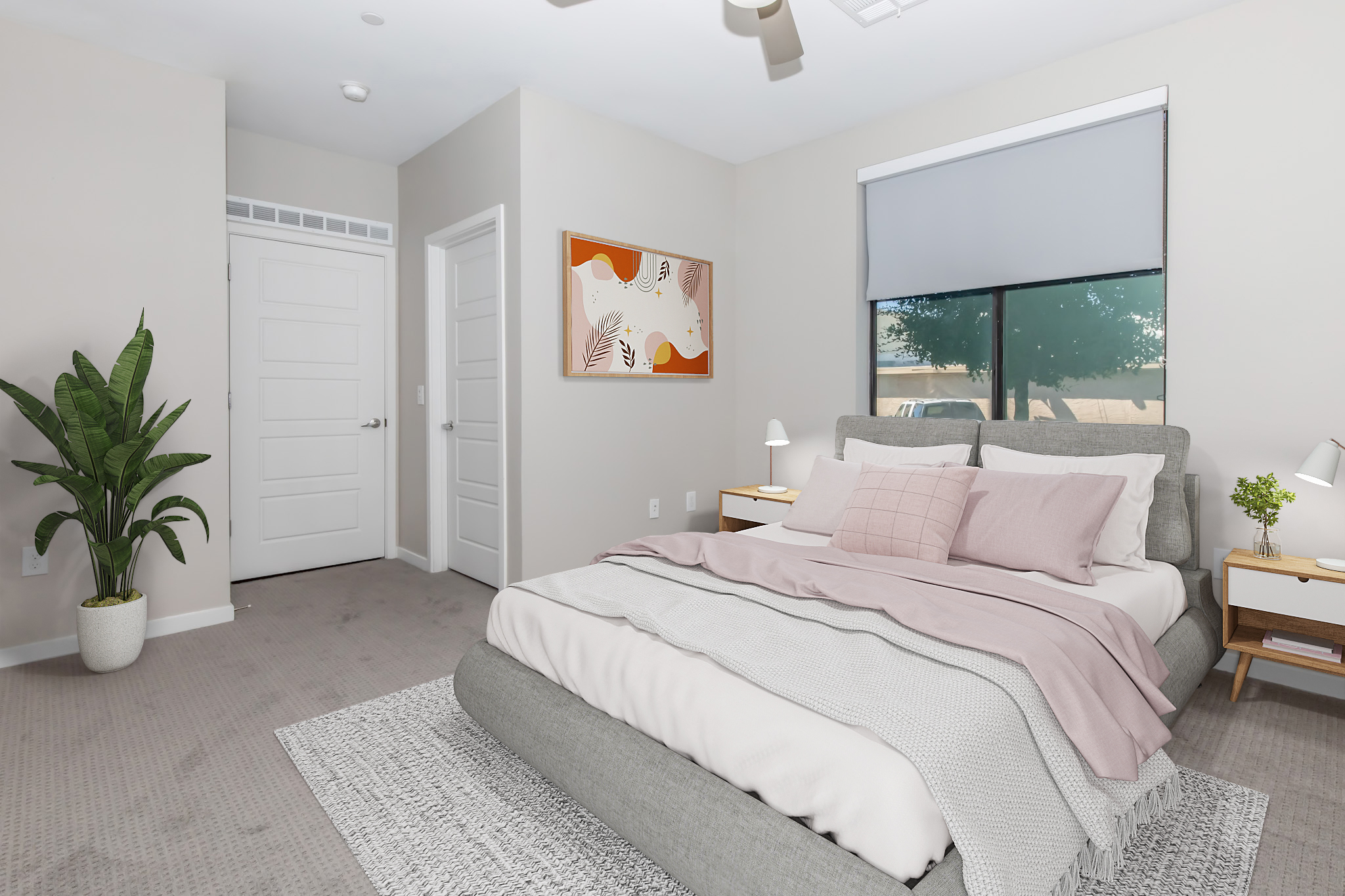 A modern bedroom featuring a plush gray bed with pink and white bedding. There are two wooden nightstands with small lamps, a large window covered by a light gray blind, and a decorative plant in the corner. A piece of abstract art hangs on the wall, complementing the neutral decor.