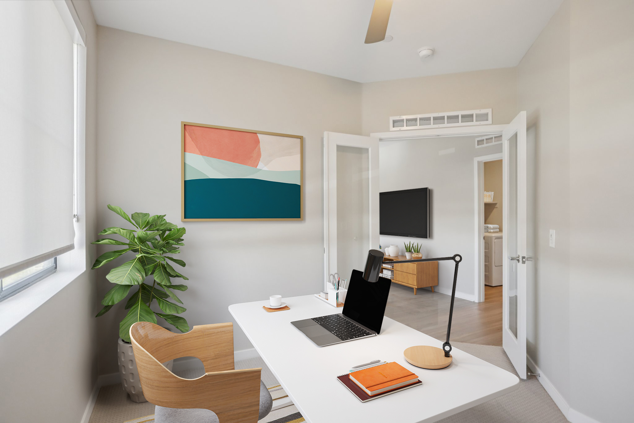 A modern home office featuring a white desk with a laptop, a notepad, and a cup. There is a stylish chair, a potted plant, and an abstract wall art piece. Light streams through large windows, illuminating the neutral-colored walls and wooden accents. A TV is mounted on the wall, adding to the contemporary aesthetic.