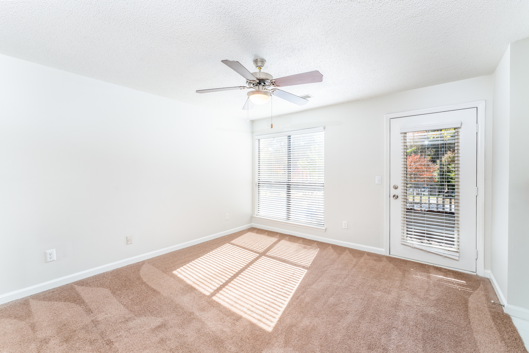 Carpeted living room with large windows at Huntsview Apartments in Greensboro, North Carolina