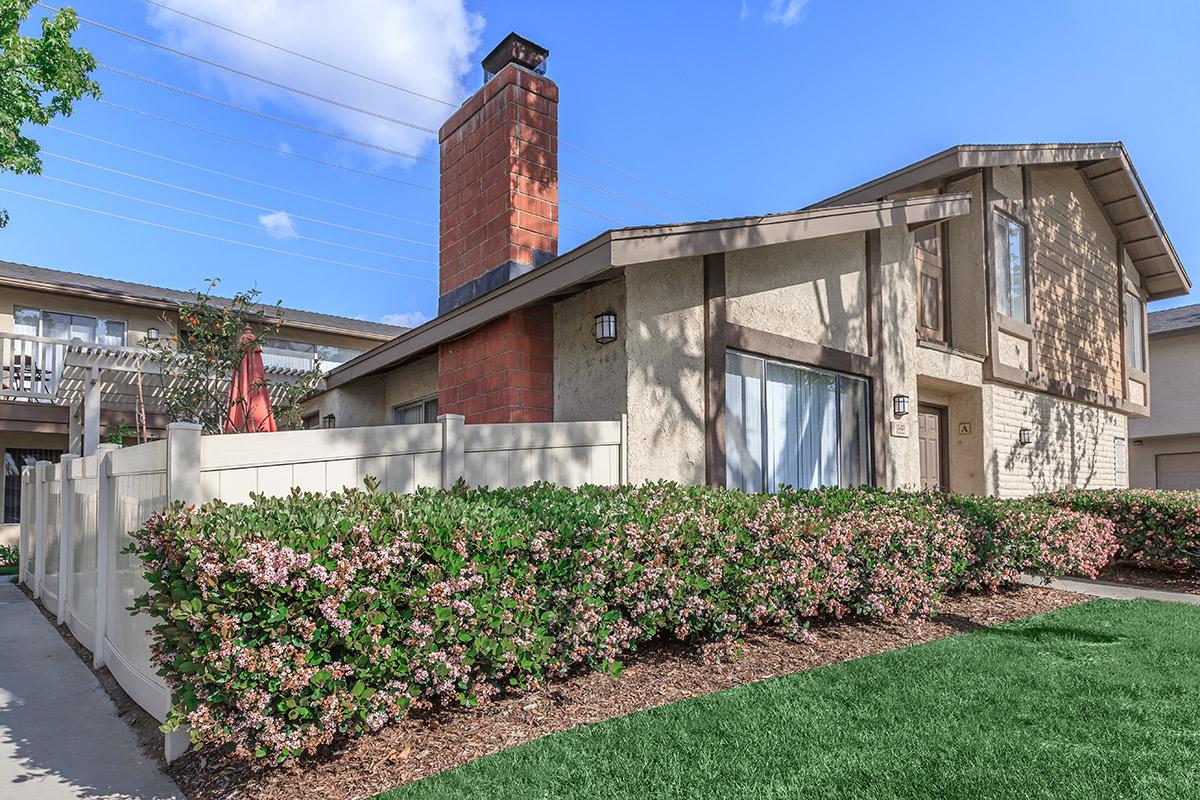 Community building with green shrubs and pink flowers