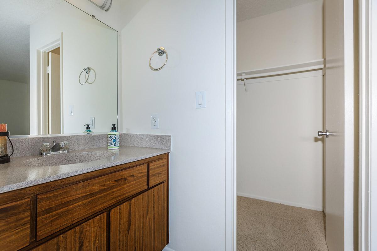 Bathroom sink with wooden cabinets and open closet door