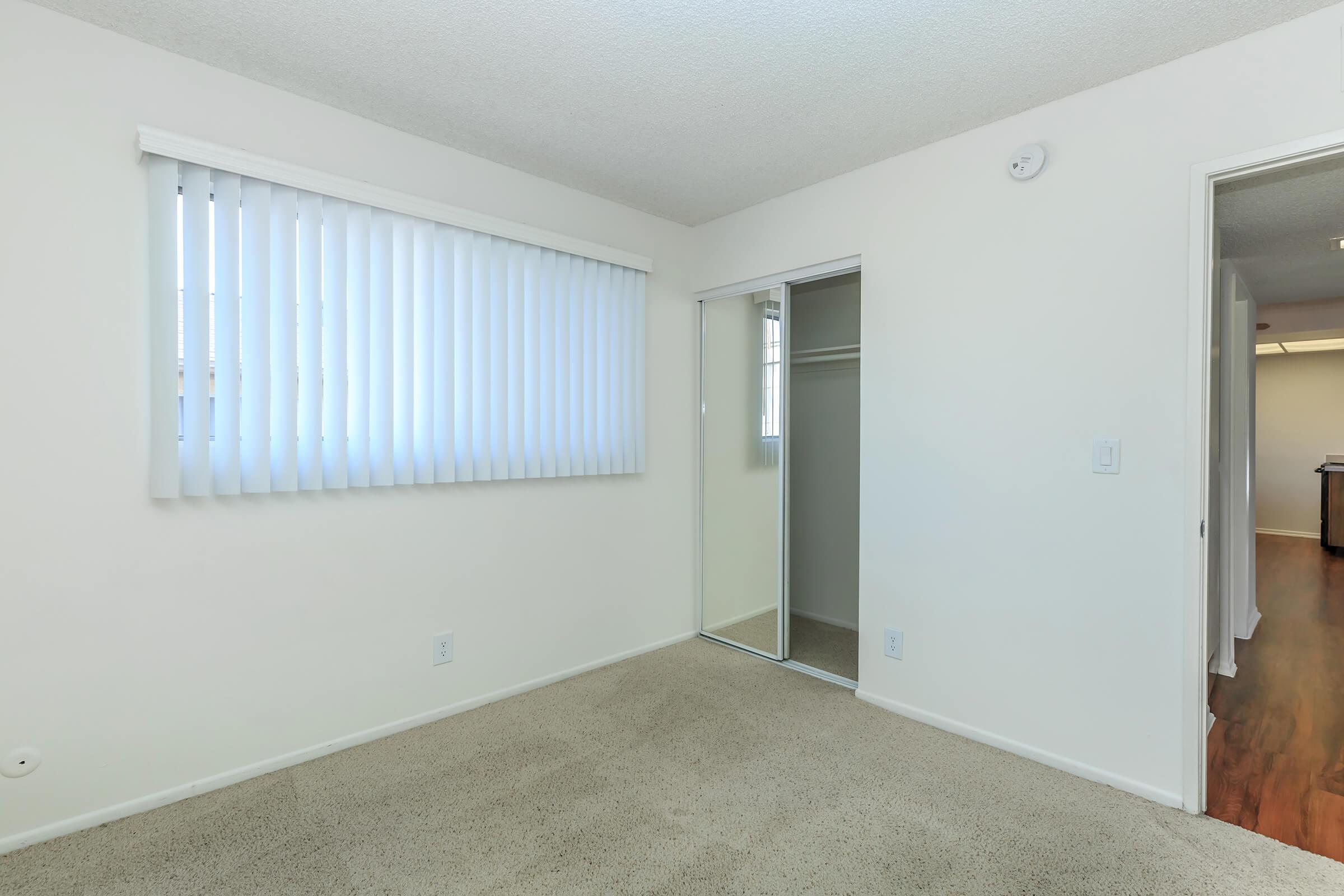 Vacant bedroom with open mirror glass sliding closet door