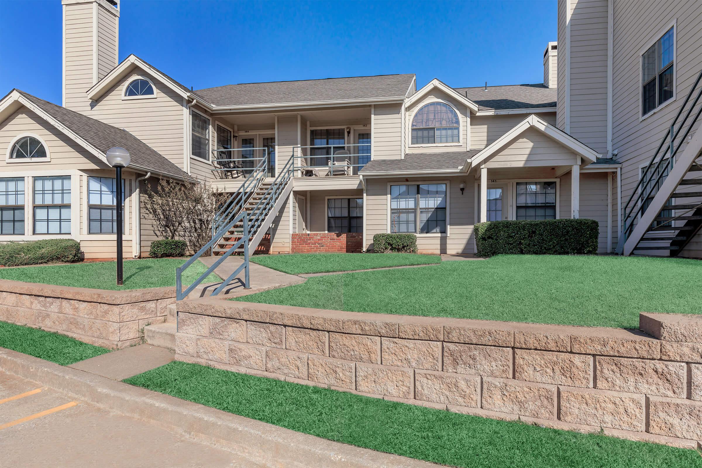 a large brick building with grass in front of a house