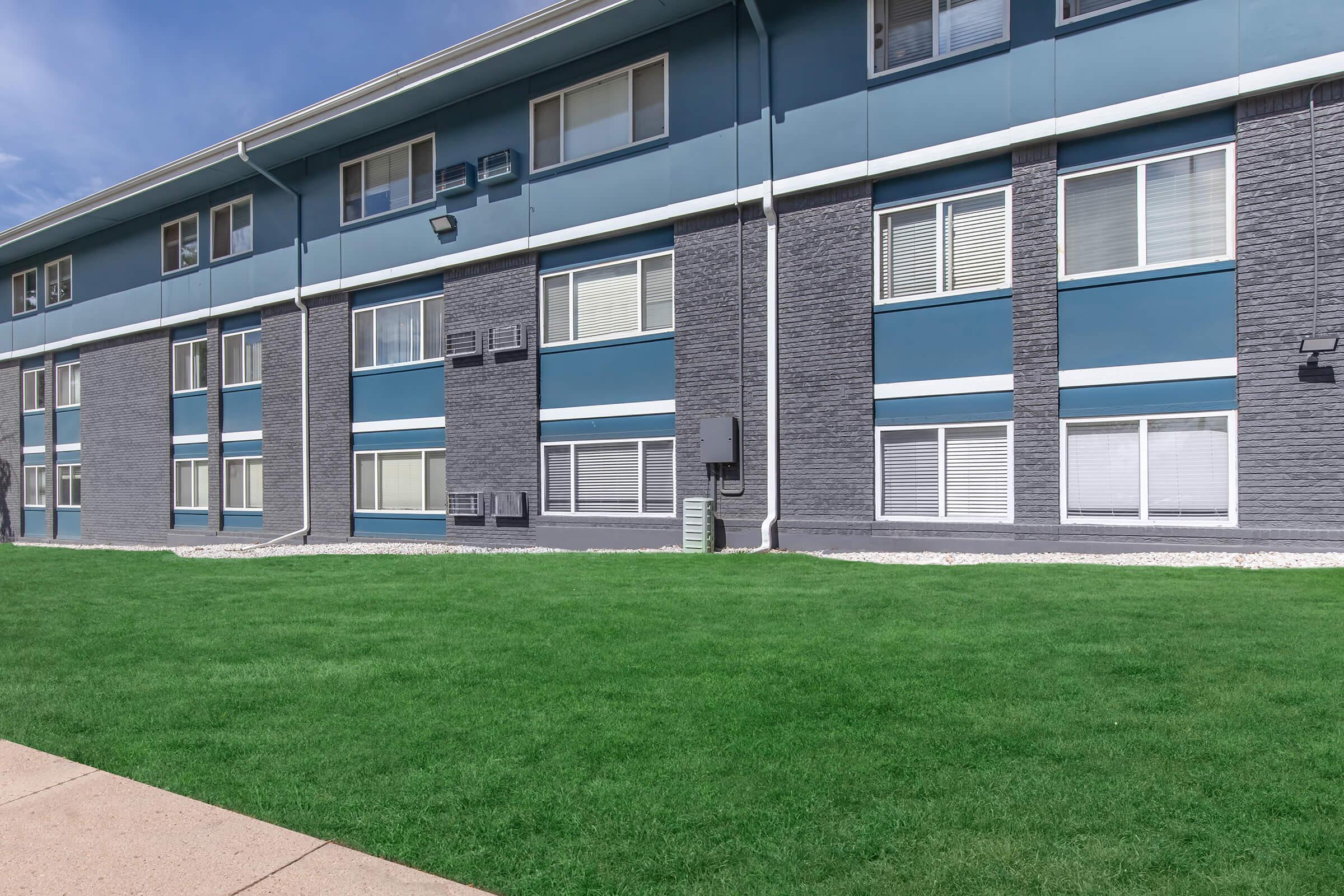 a large brick building with green grass