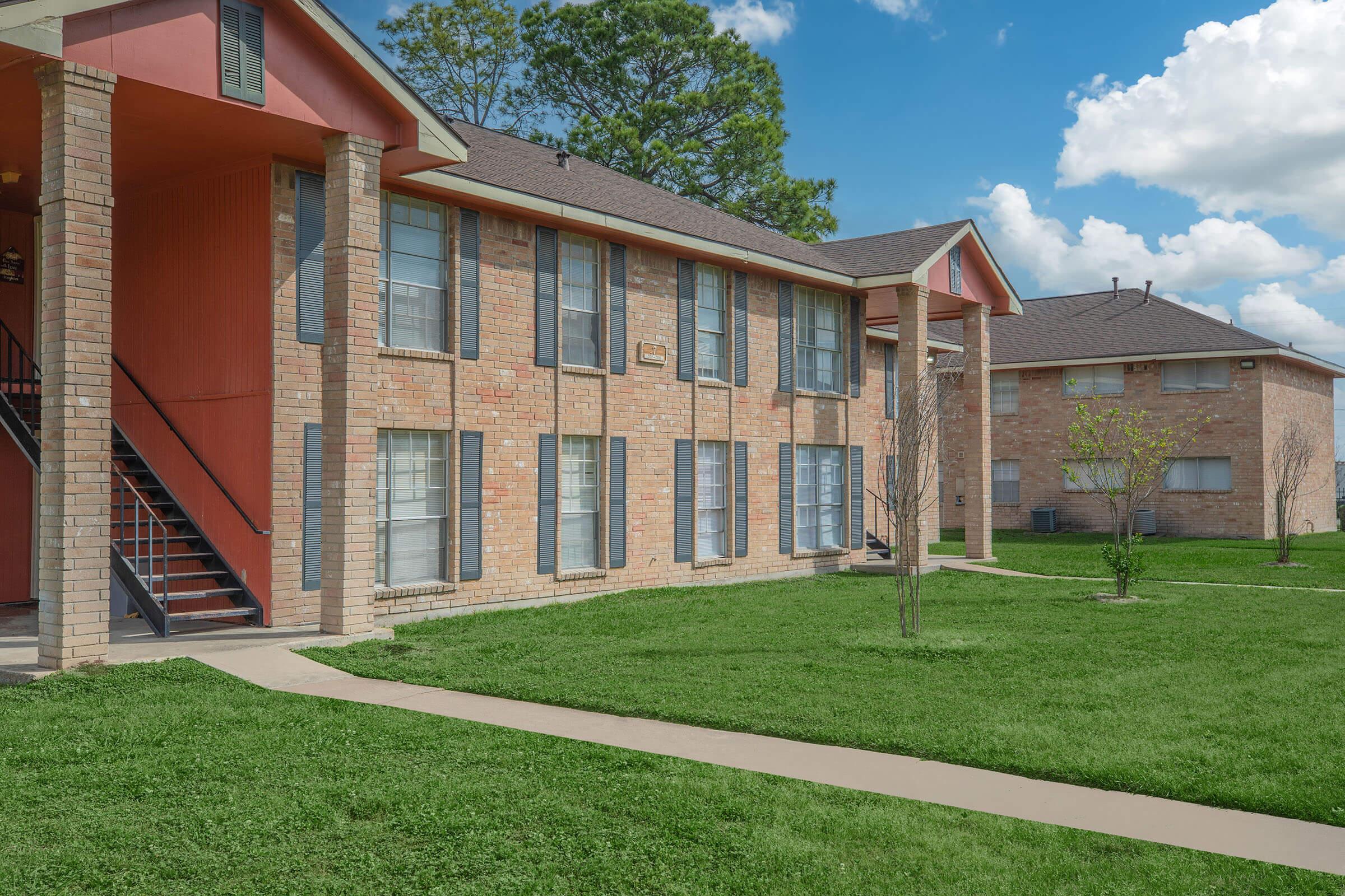 a large brick building with grass in front of a house