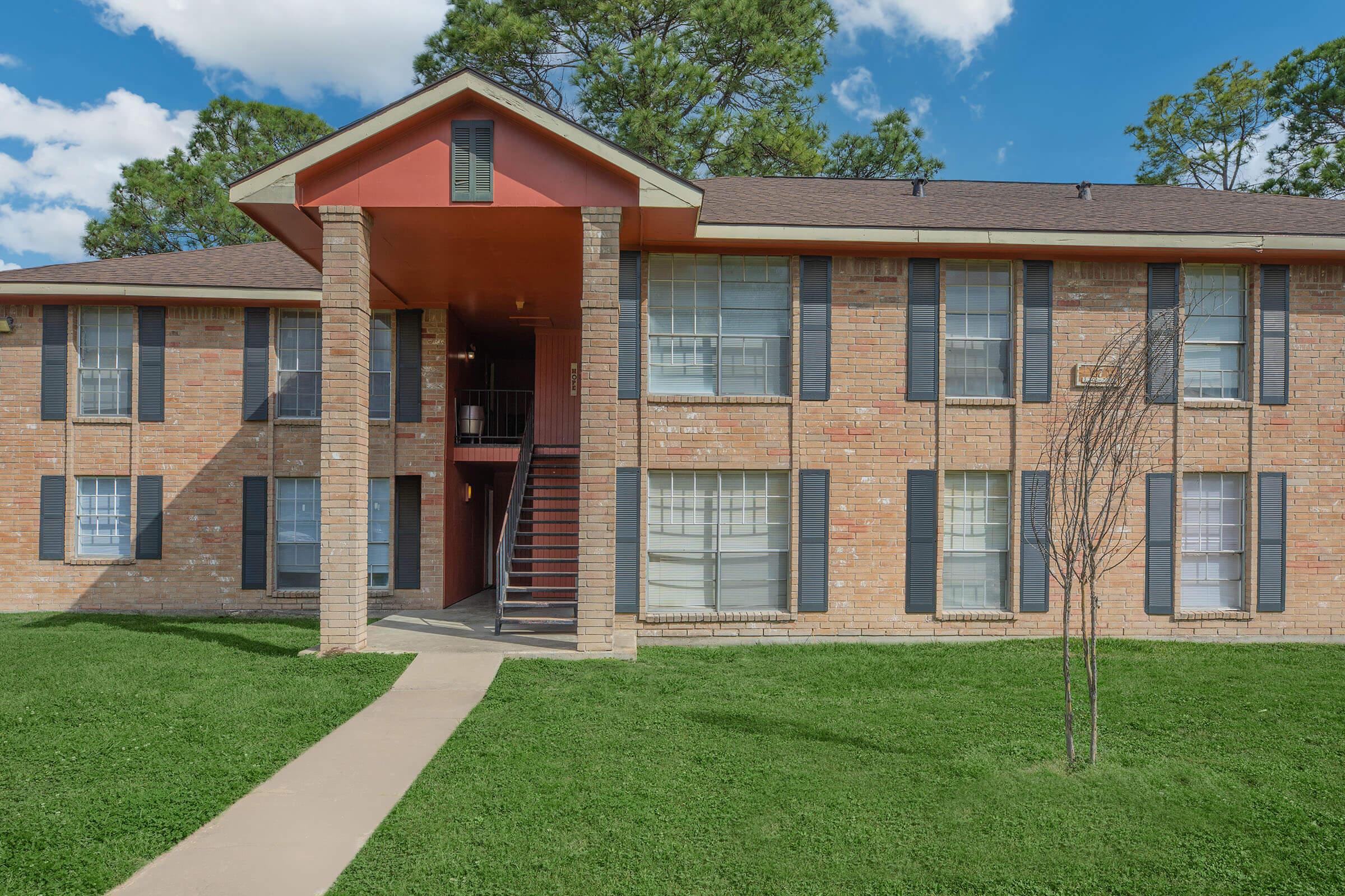 a large brick building with grass in front of a house