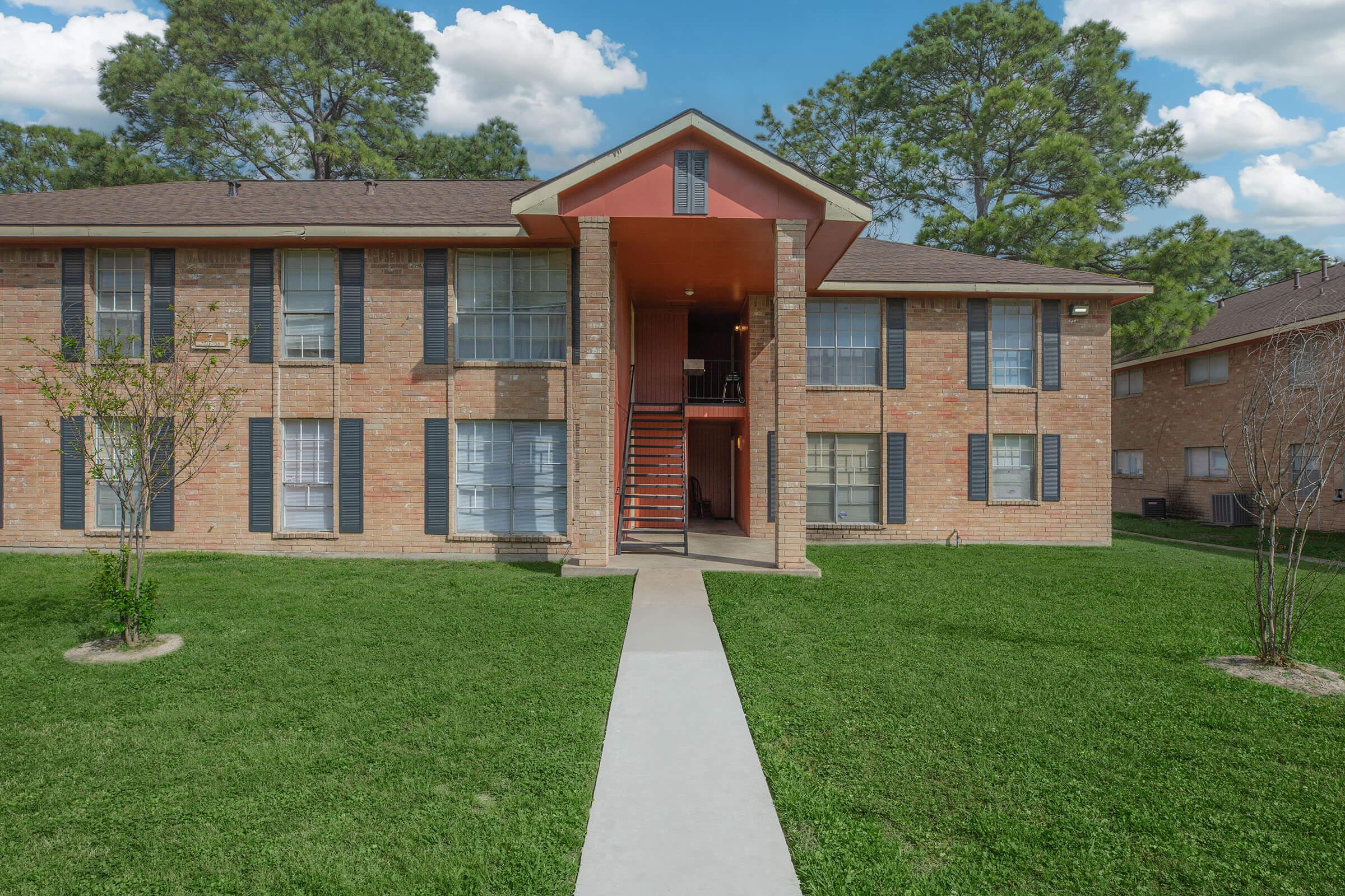 a house with a lawn in front of a brick building