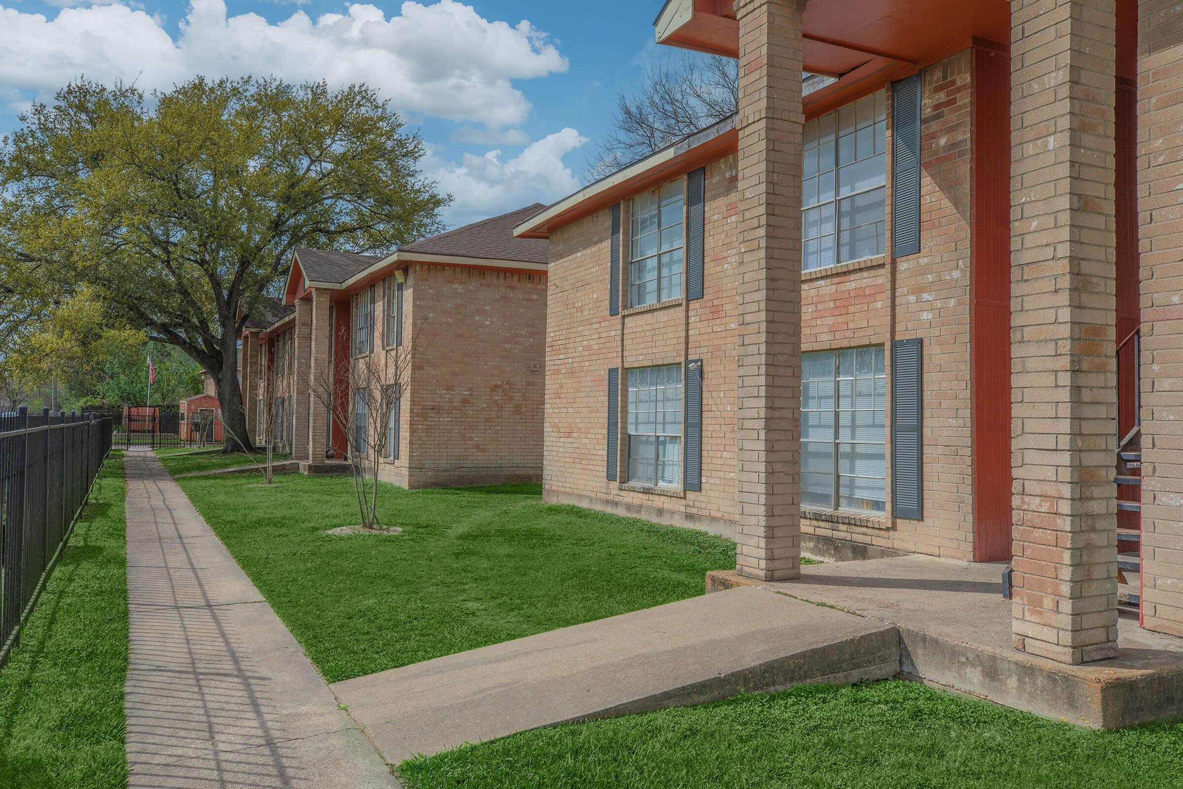 a large brick building with grass in front of a house