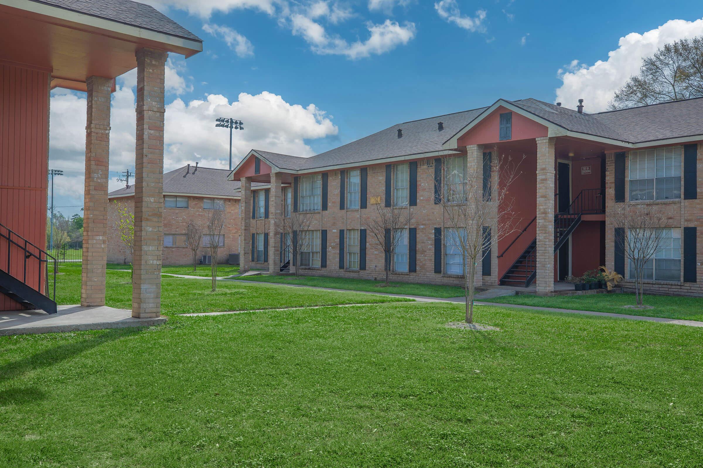 a large brick building with grass in front of a house