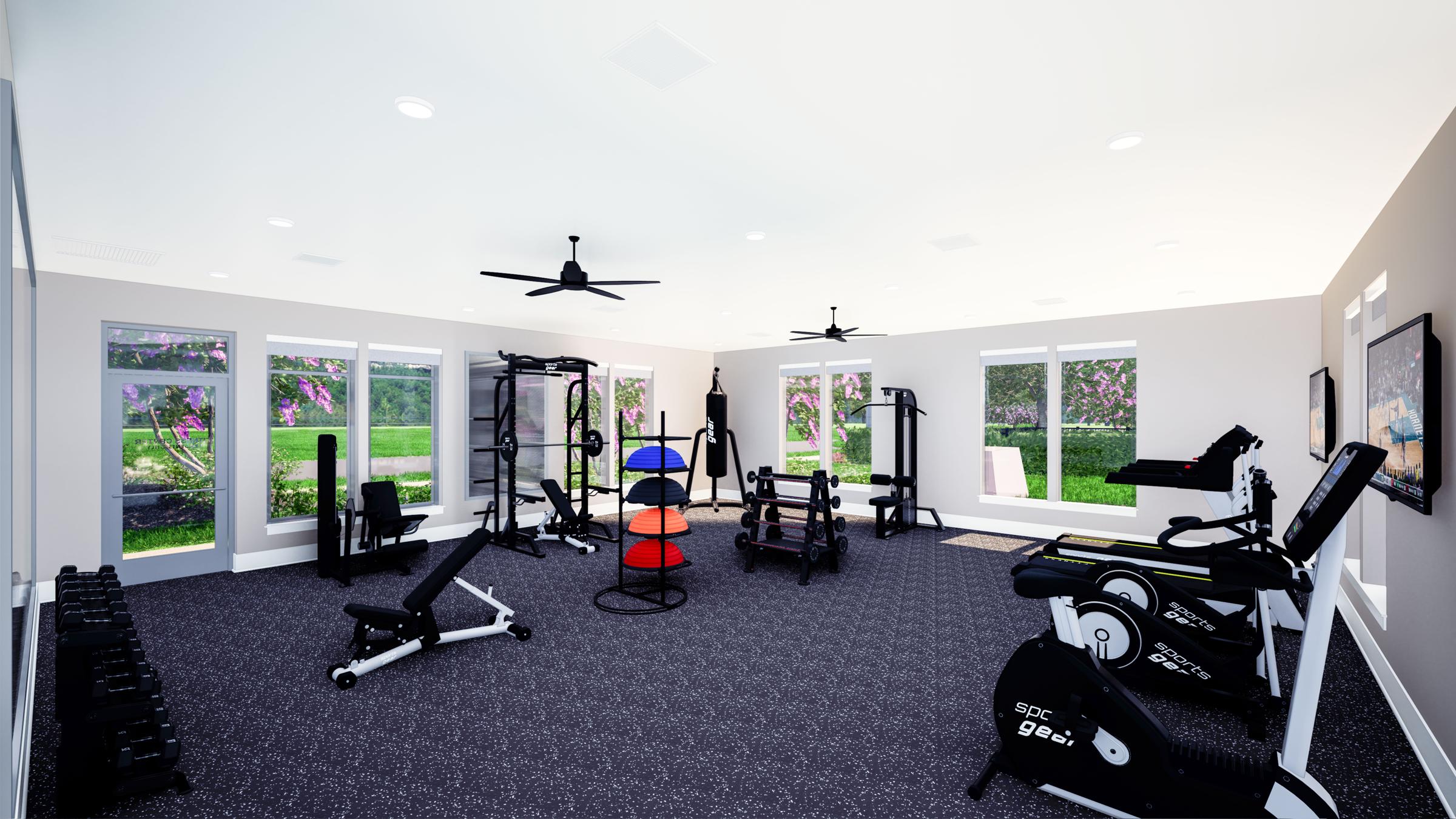 A modern gym interior featuring various fitness equipment, including weights, exercise machines, and multi-use strength training stations. The space is well-lit with large windows offering views of greenery outside, and is designed with a clean, contemporary aesthetic.