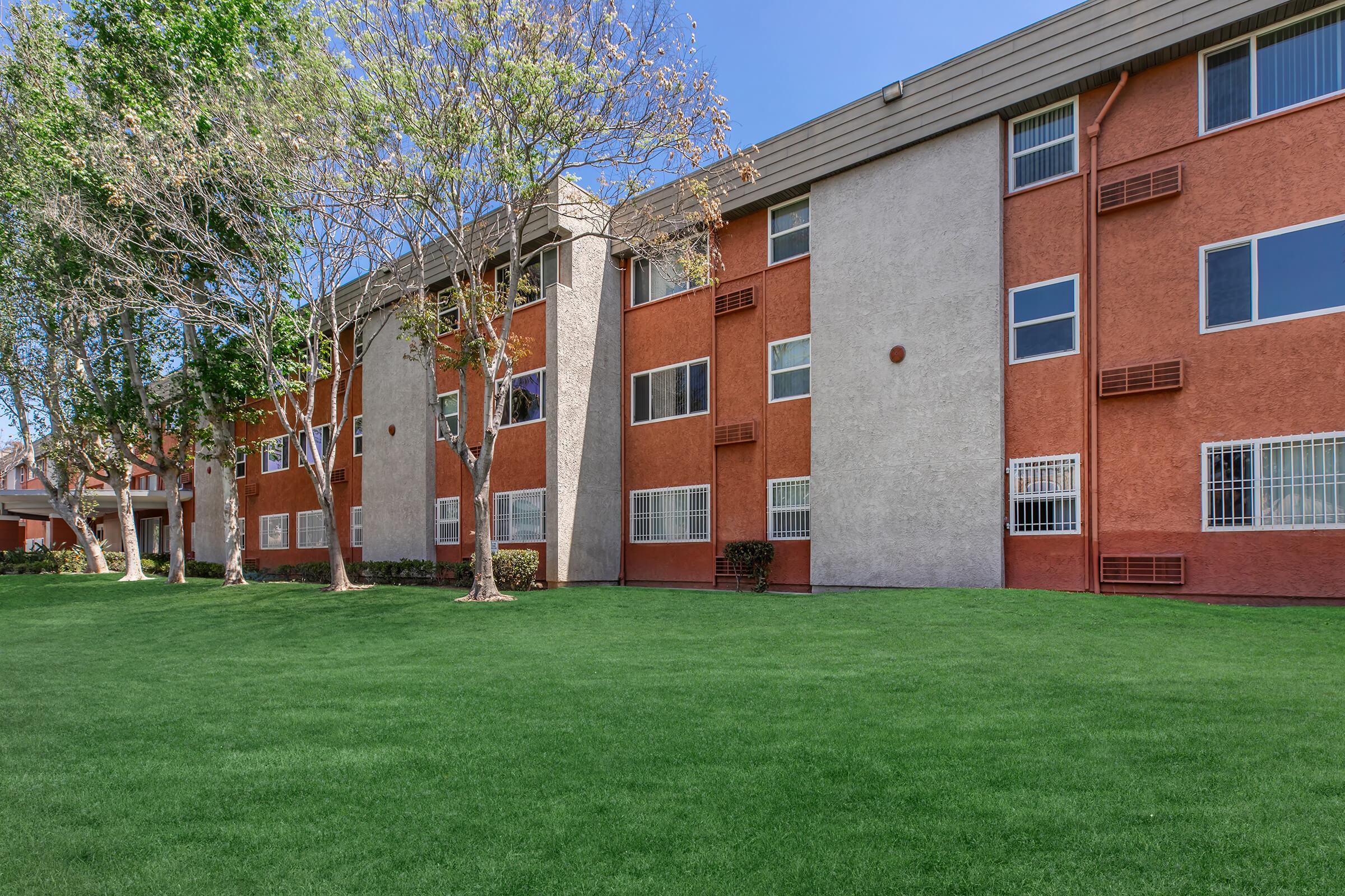 a large brick building with a grassy field