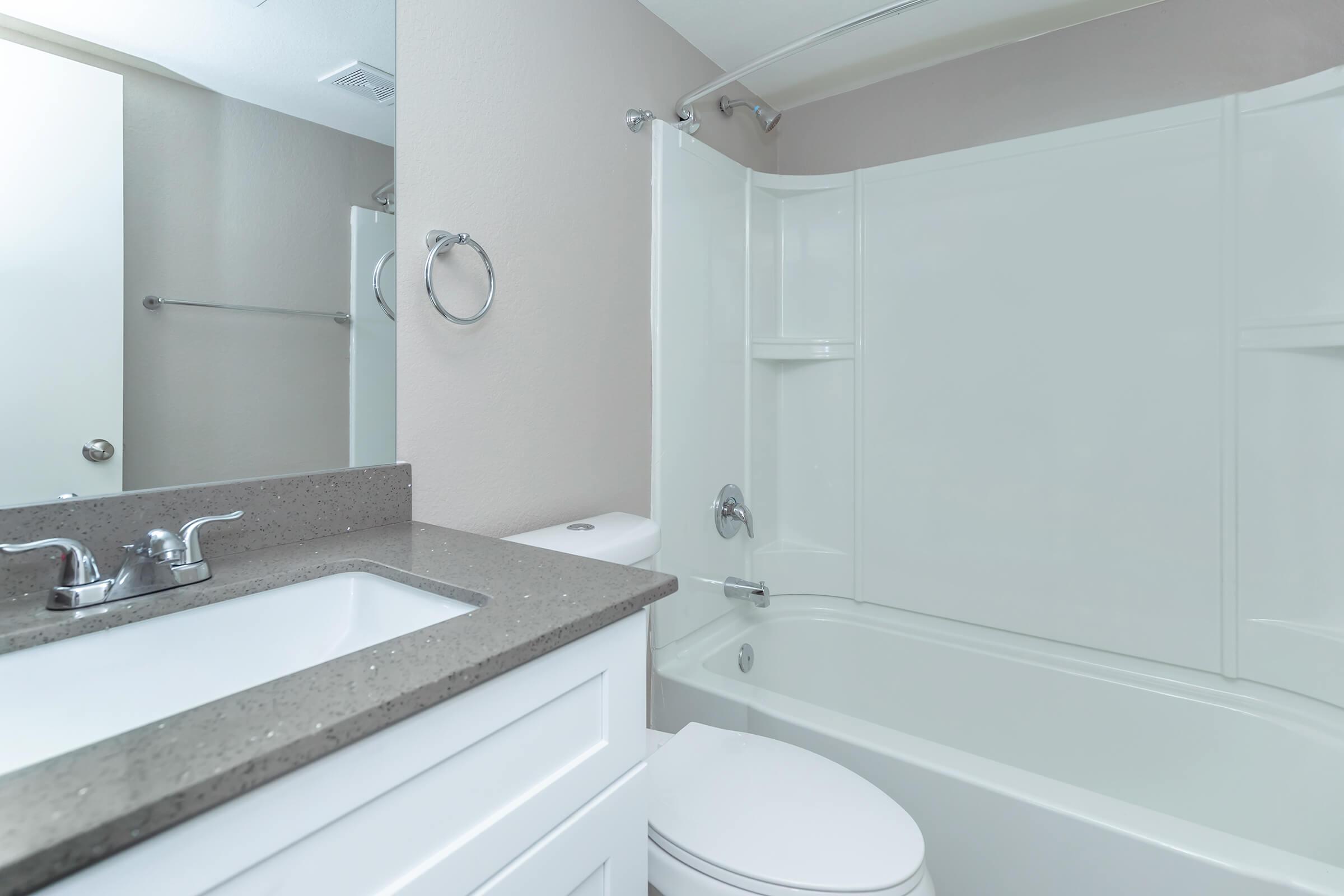 Modern bathroom with tub shower, toilet, and mirrored vanity