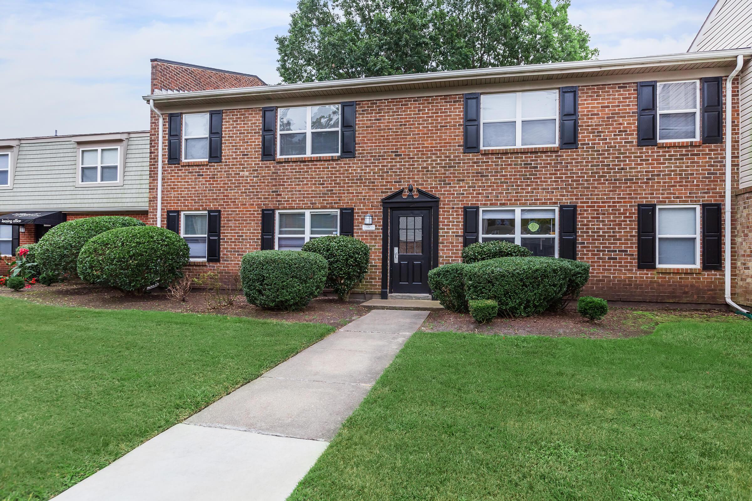 a house with a lawn in front of a brick building