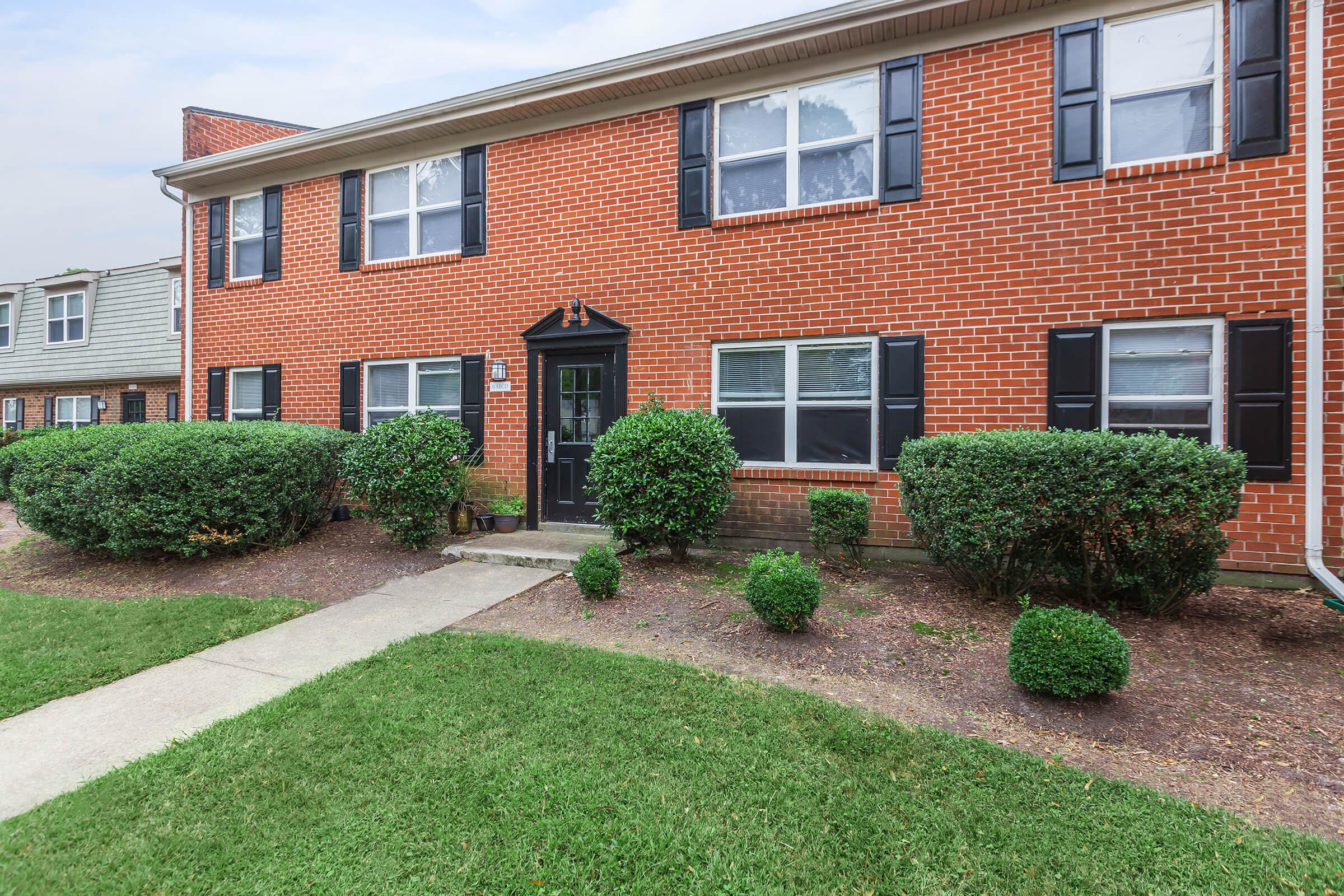 a large brick building with grass in front of a house