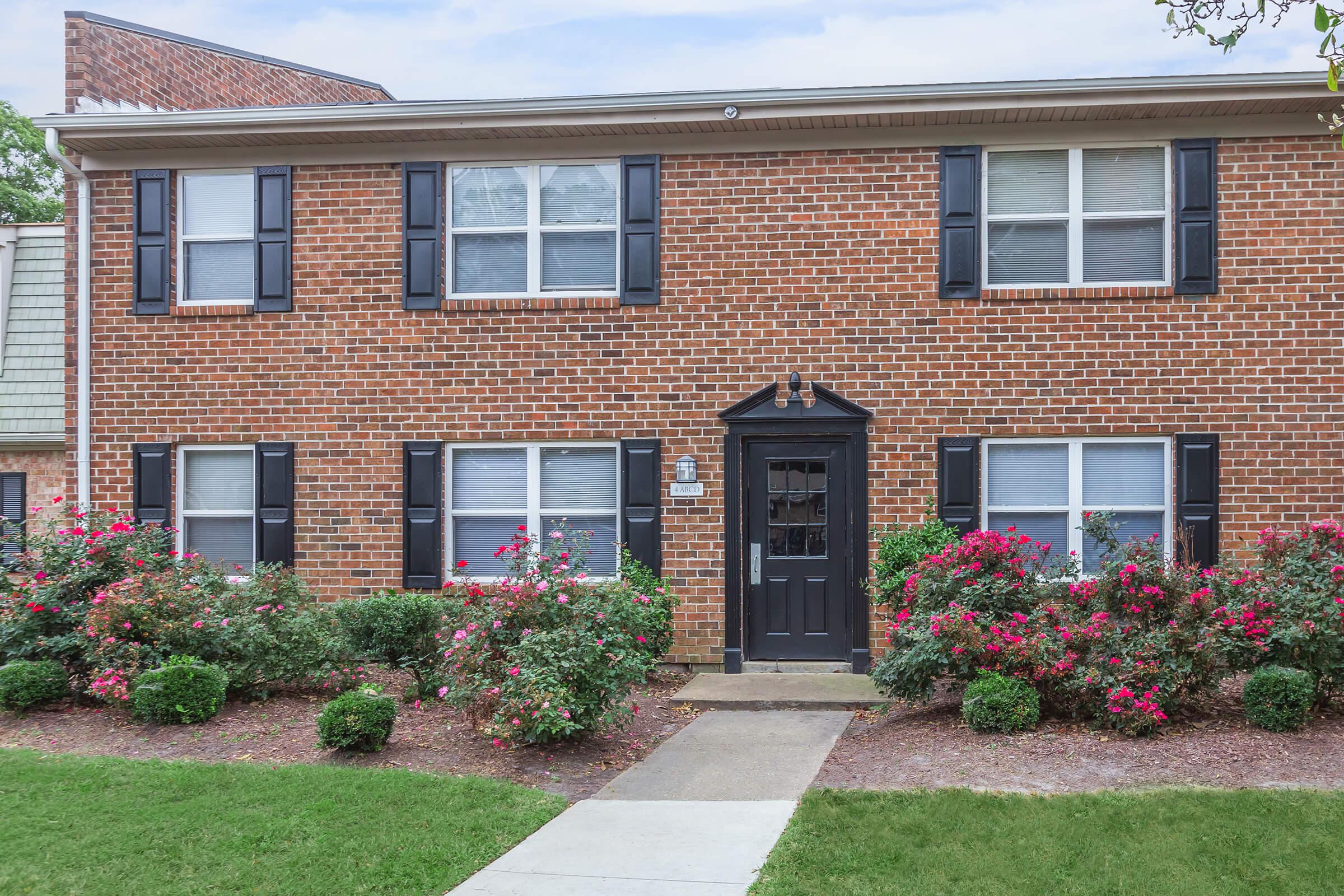 a large brick building with grass in front of a house