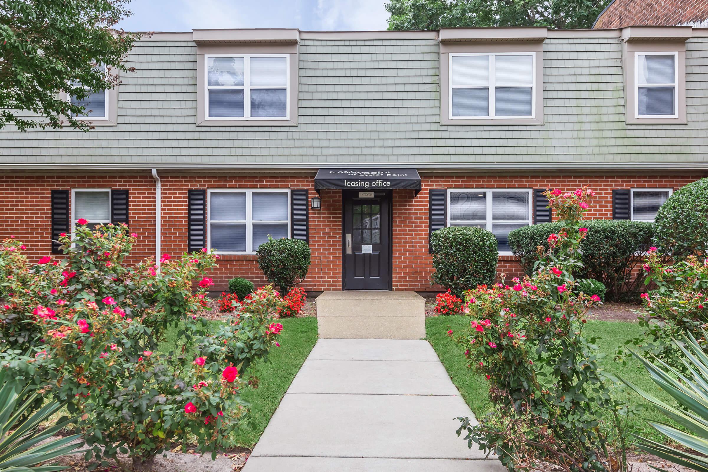 a close up of a flower garden in front of a brick building